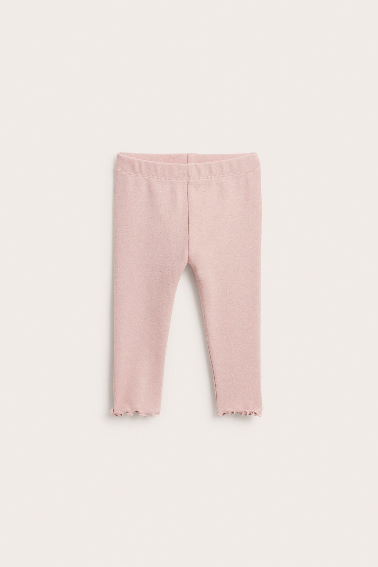 Widok z przodu, jednolite różowe legginsy niemowlęce pointelle z elastyczną talią i falbankowym wykończeniem.