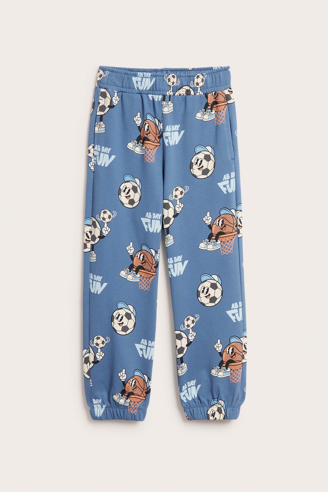 Forfra, blå mønstrede kosedressbukser for barn med sportsballgrafikk og teksten 'ALL DAY FUN'.