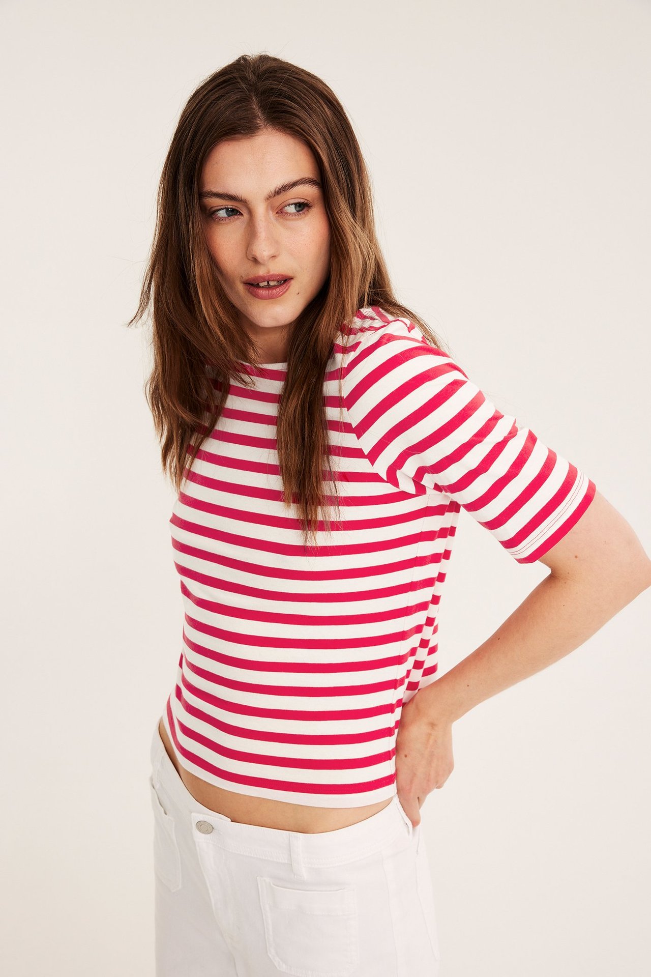 Edestä kuvattu nainen yllään punavalkoraidallinen lyhythihainen venekaula-aukkotoppi ja valkoiset housut.
