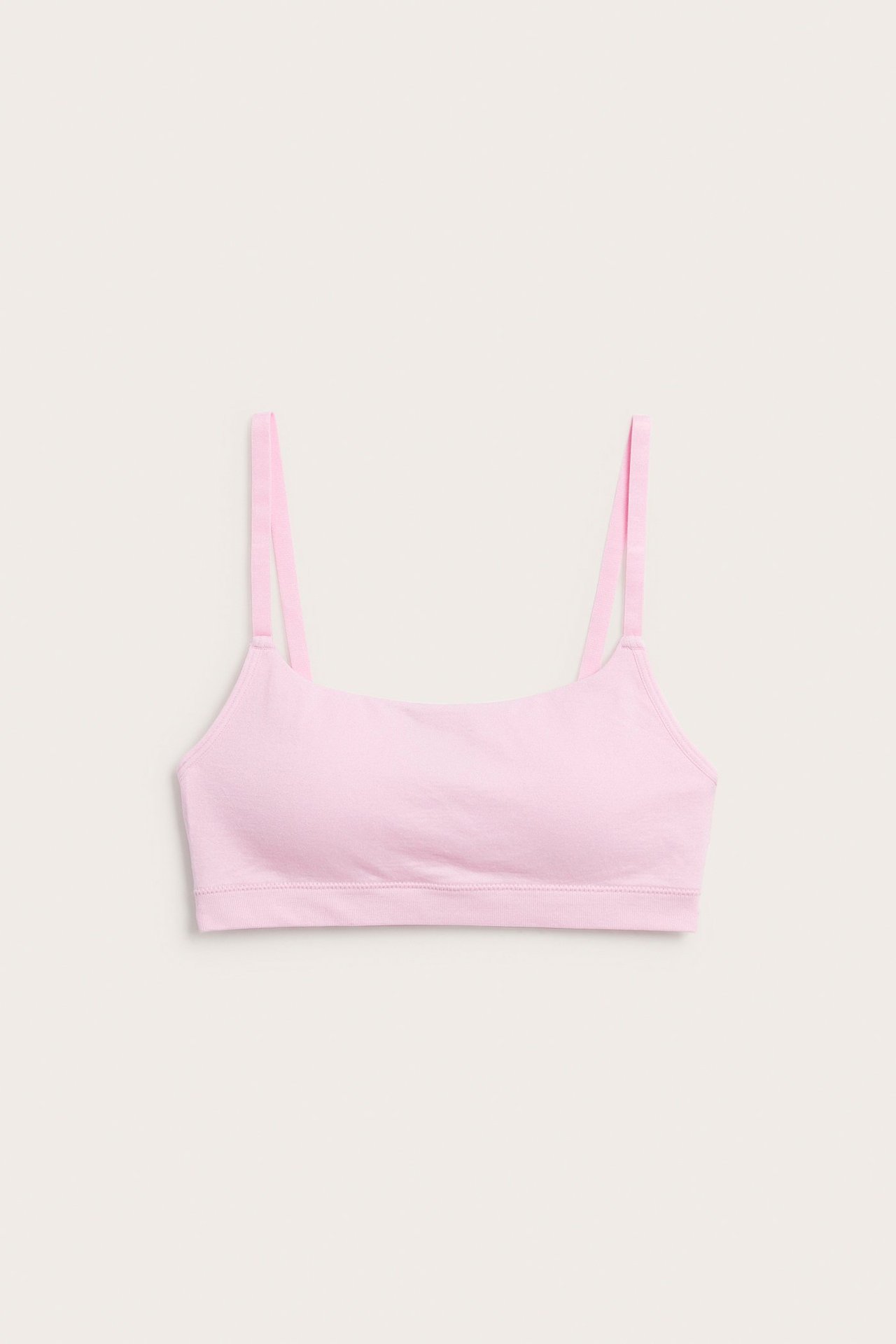 Framifrån, en enfärgad rosa seamless-bh med justerbara axelband.