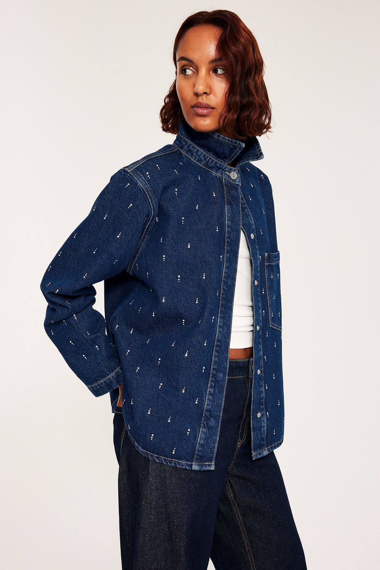 Dam i denimskjorta med glitterdetaljer, hög krage och dragkedja, enkel stil.