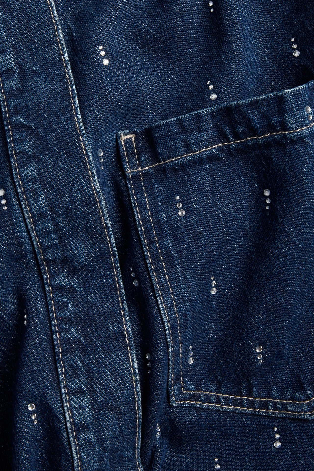 Zbliżenie na ciemnoniebieską koszulę dżinsową z bawełny z kieszenią i cyrkoniami.