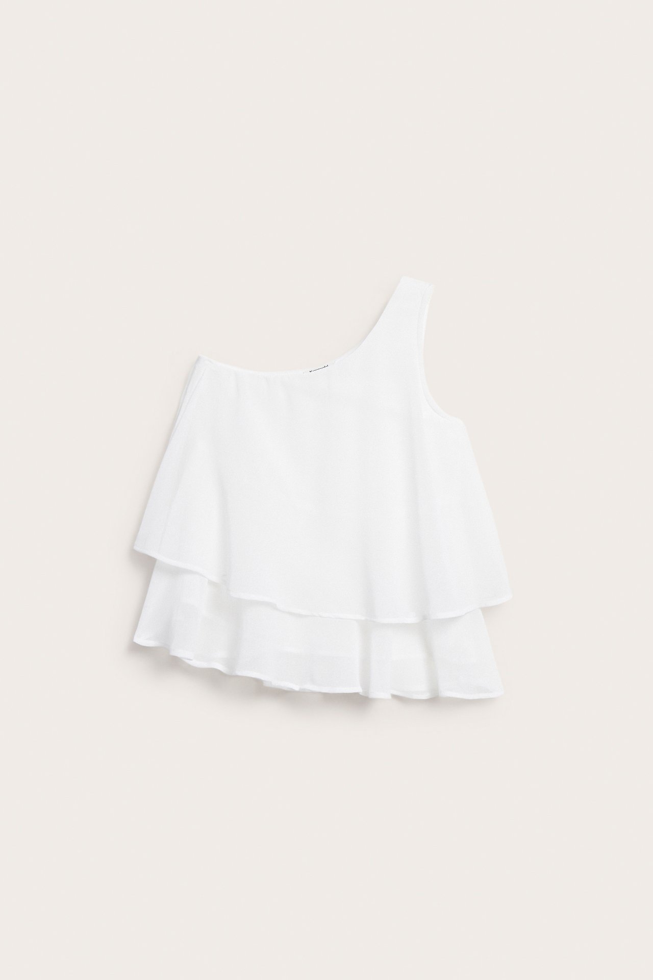 Widok z przodu białej bluzki na jedno ramię z dwoma warstwowymi falbanami.