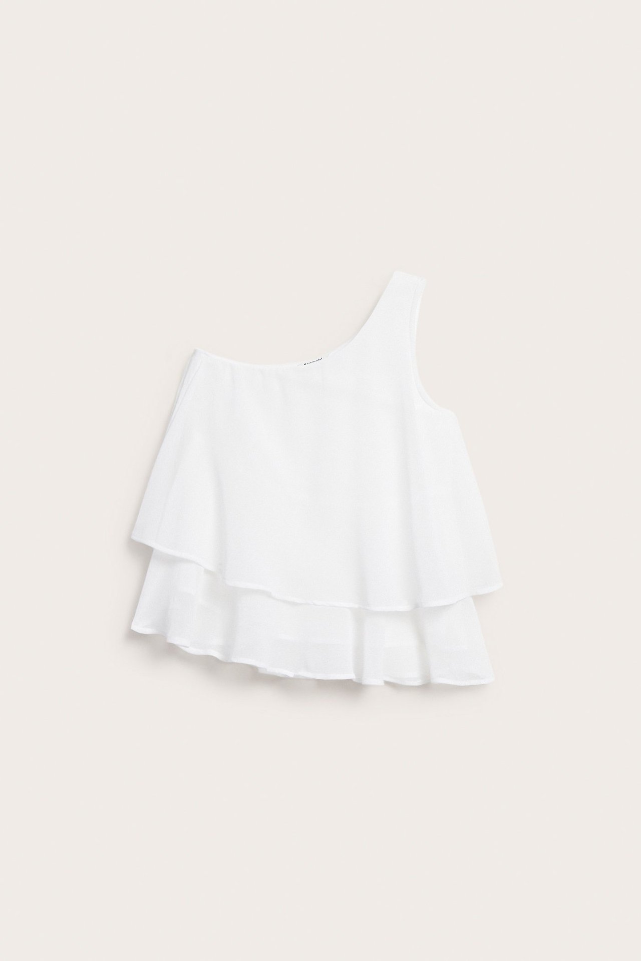 Frontvy av en vit one-shoulder blus med två vågiga volanger.