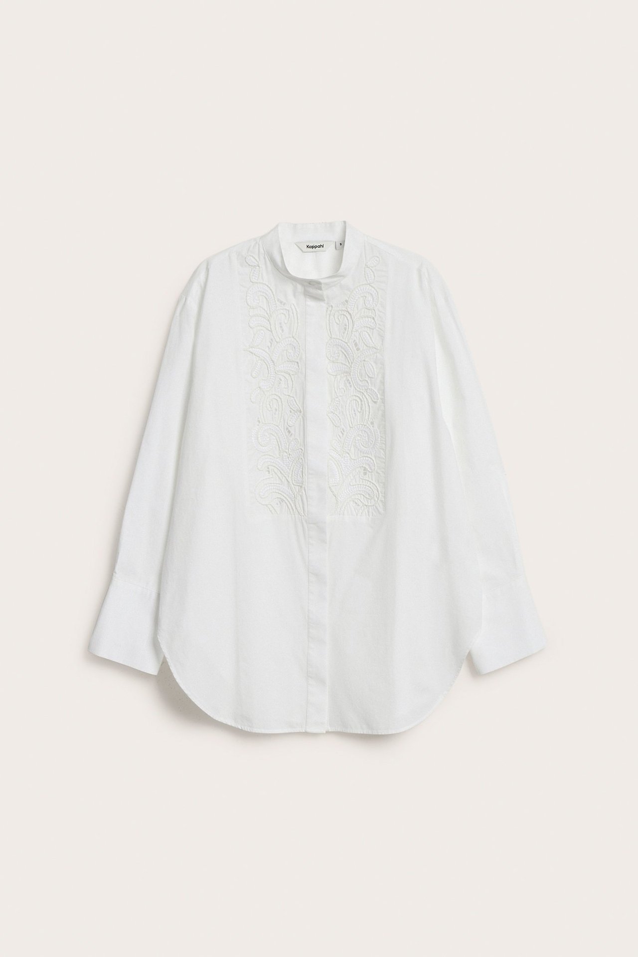 Edestä näkymä valkoisesta pitkähihaisesta puuvillapaidasta, jossa on pystykaulus ja etukirjonta.