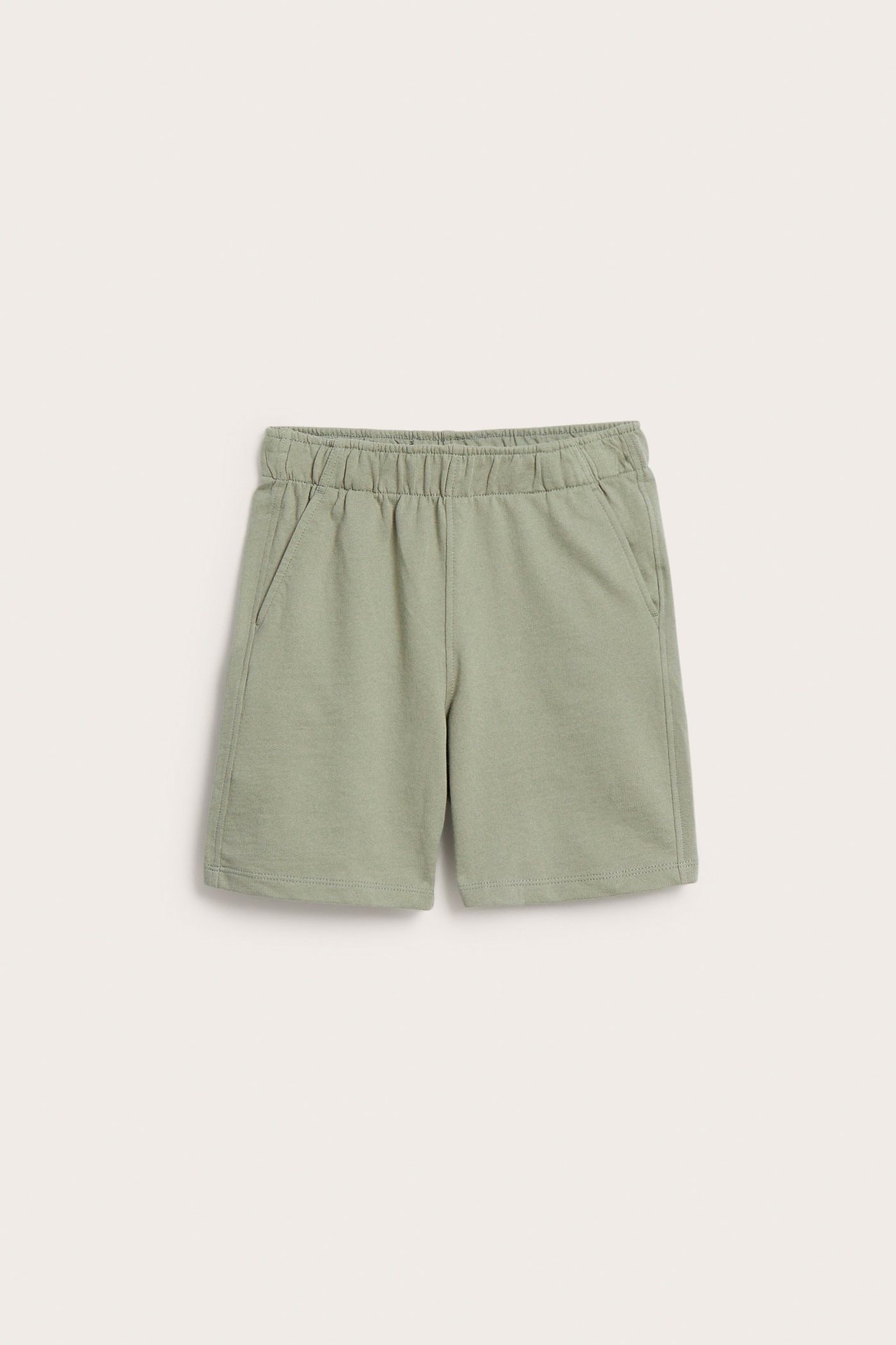Framsida av ljusgröna mjukisshorts för barn i bomull, med resår i midjan och sidofickor.
