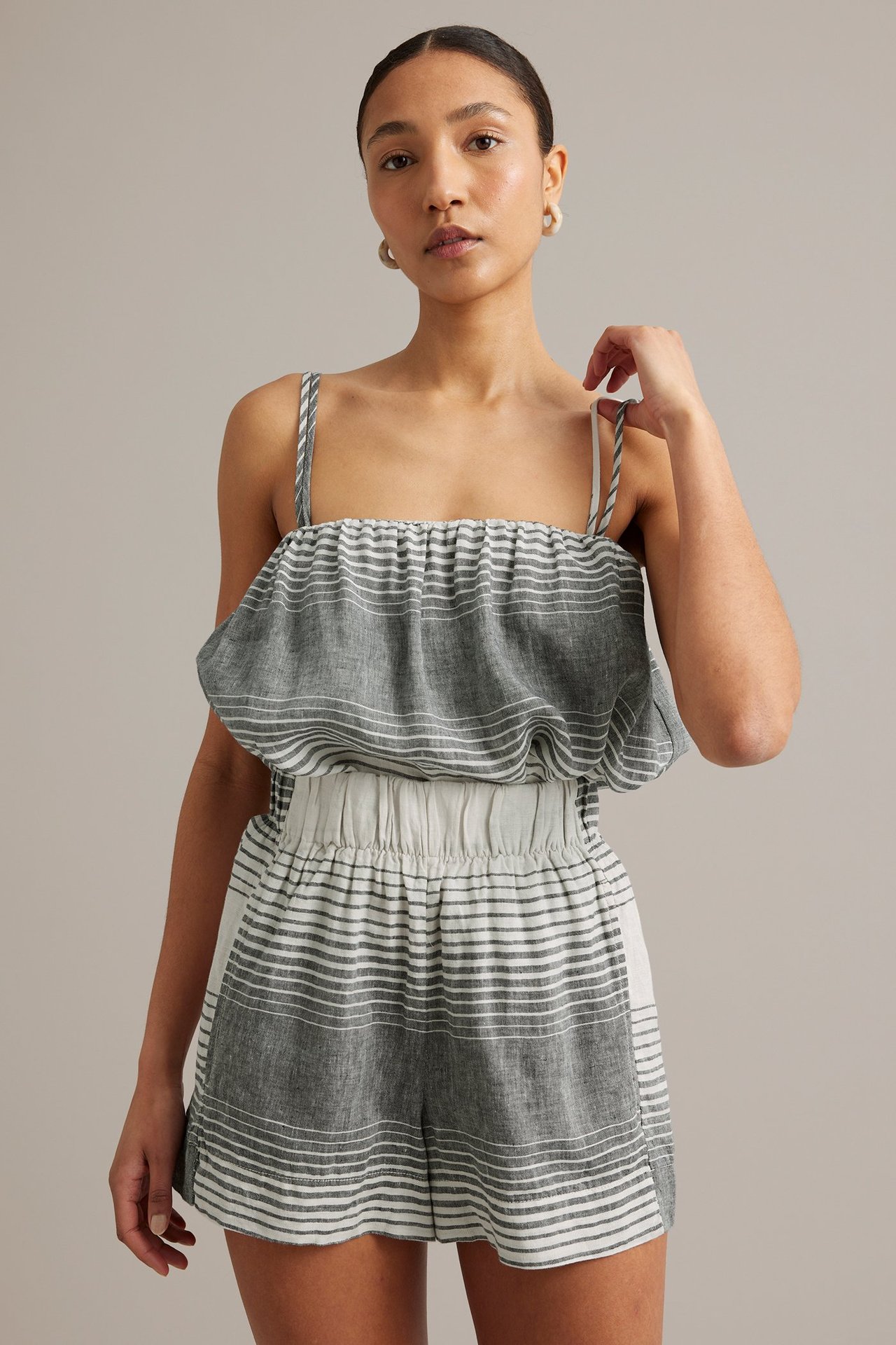Frontbilde av en kvinne i mørkeblått og hvitstripet lintopp med tynne stropper og matchende shorts.