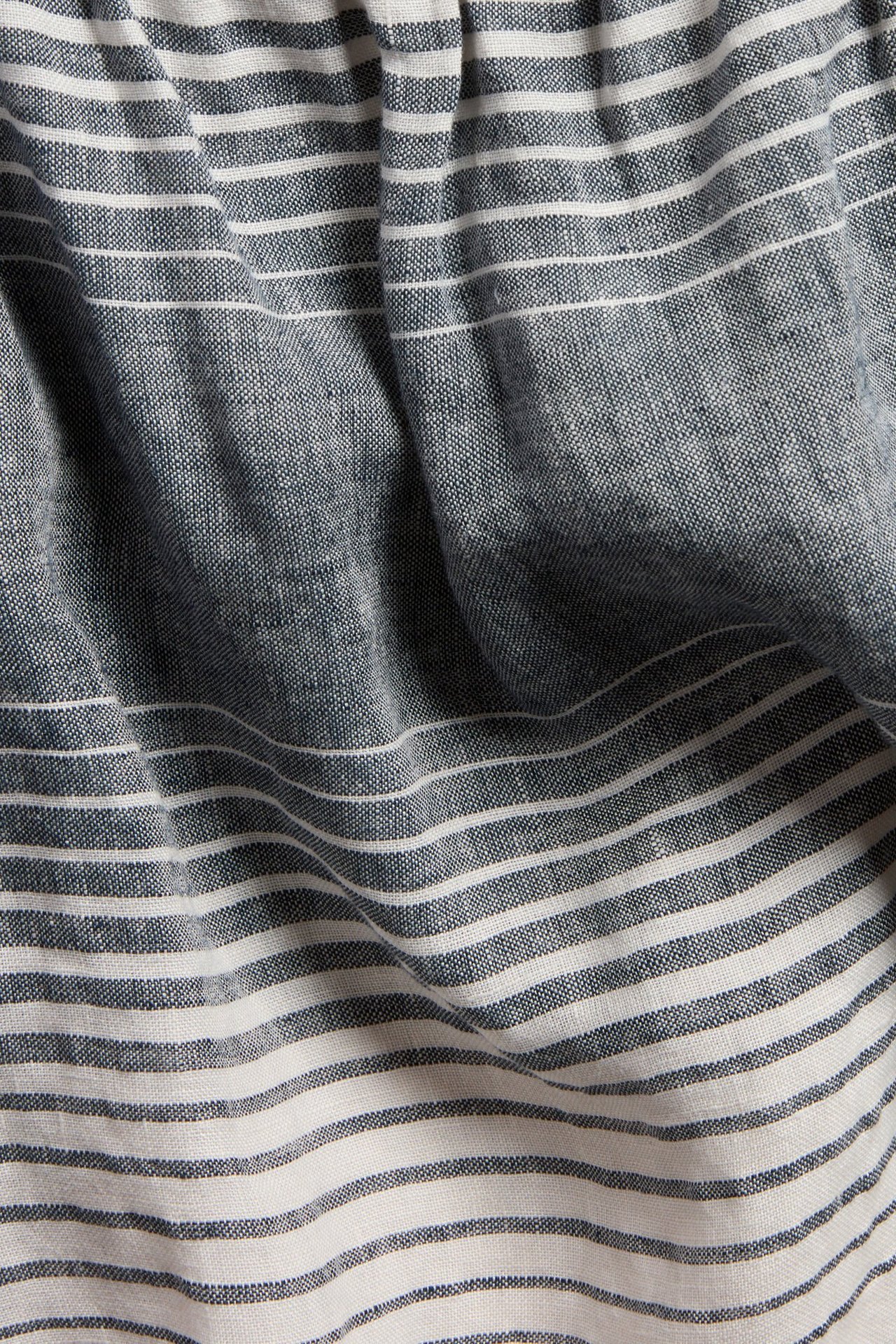 Närbild av randigt linne i mörkblått och vitt med naturliga veck.