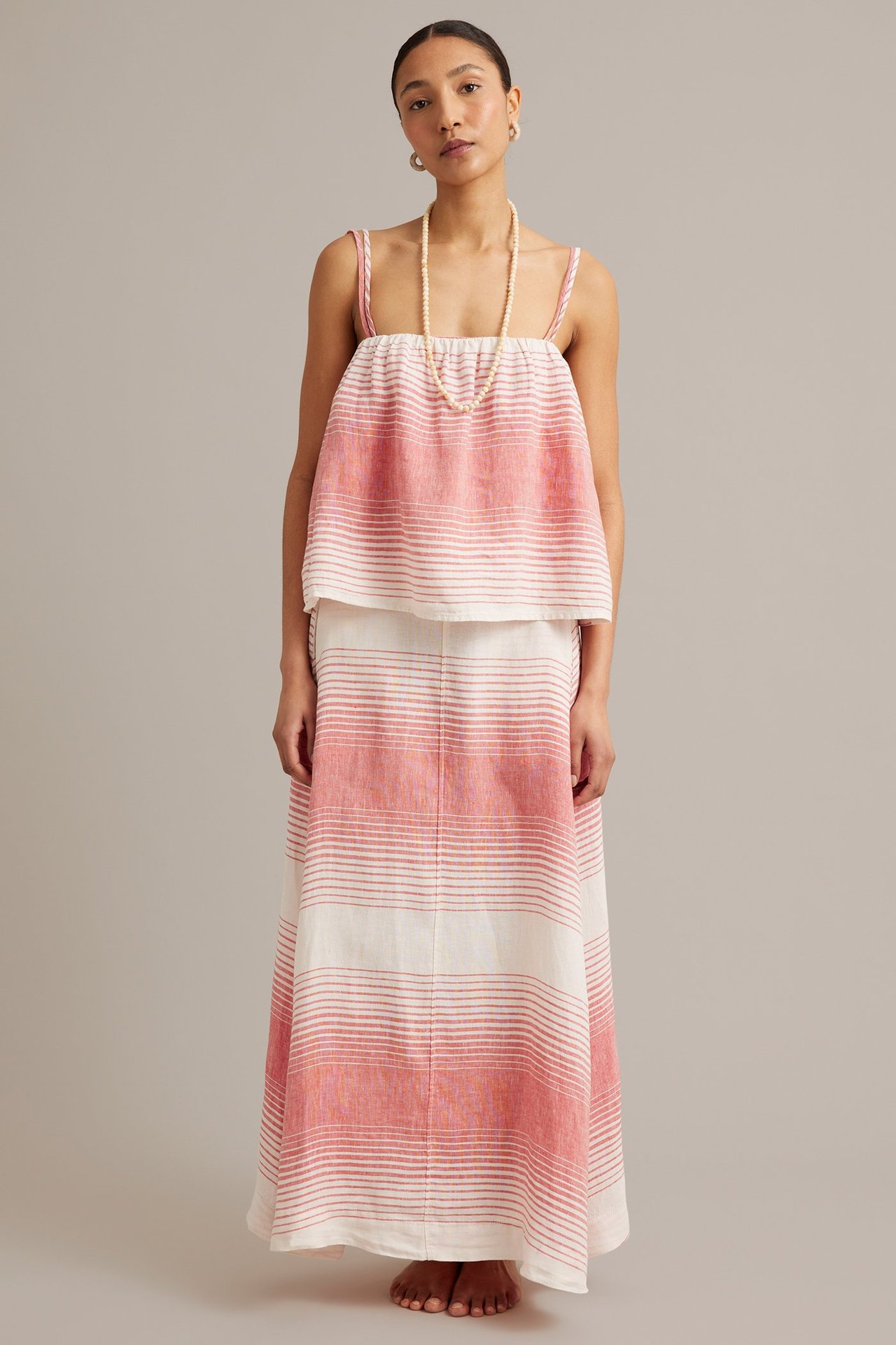 Frontutsikt: Kvinne i rødt og hvitt stripet linne med smale stropper og matchende langt skjørt.