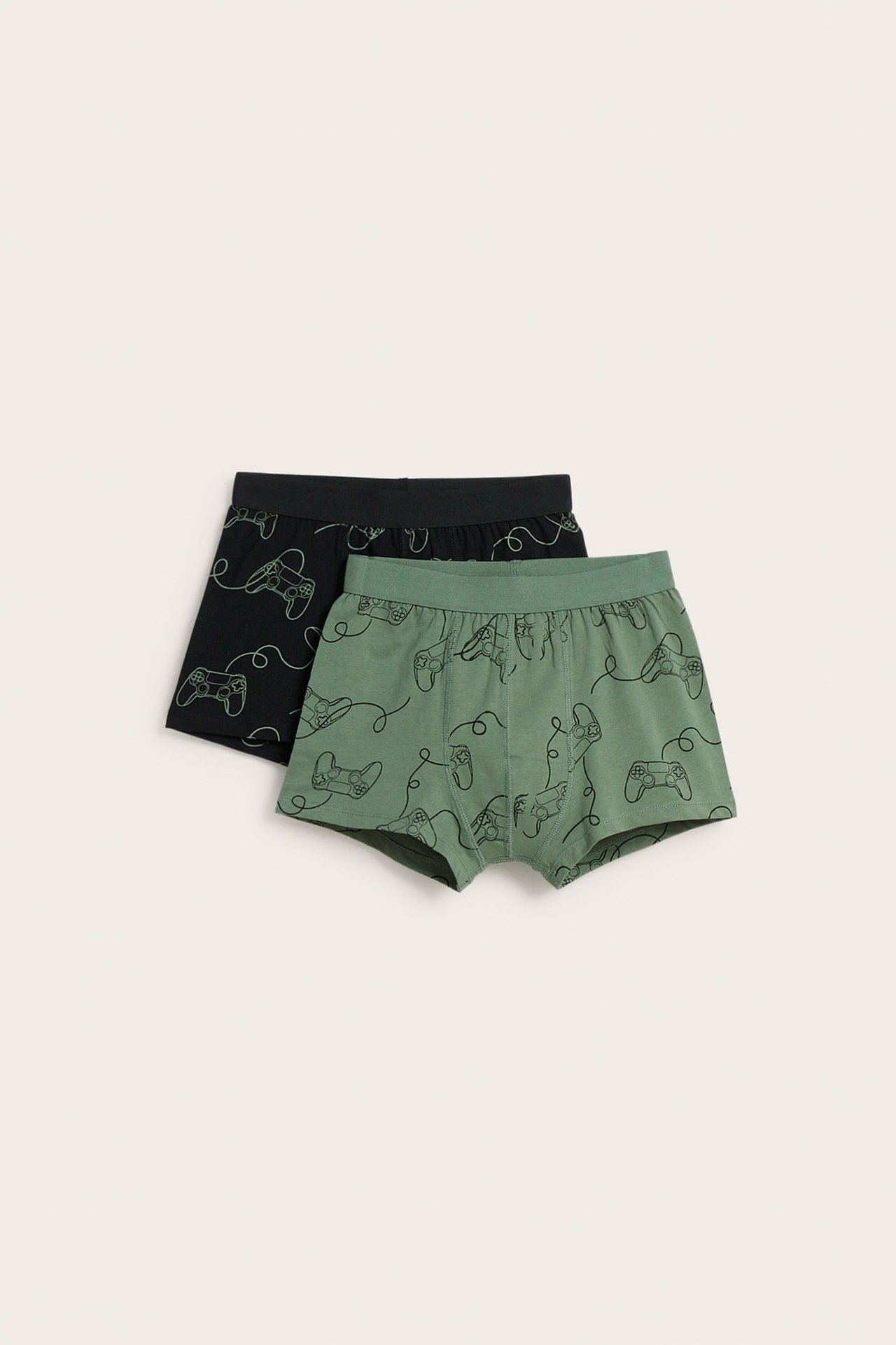 Frontalvisning av to par mønstrede boksershorts, en grønn og en svart, med spillkontrolltrykk.