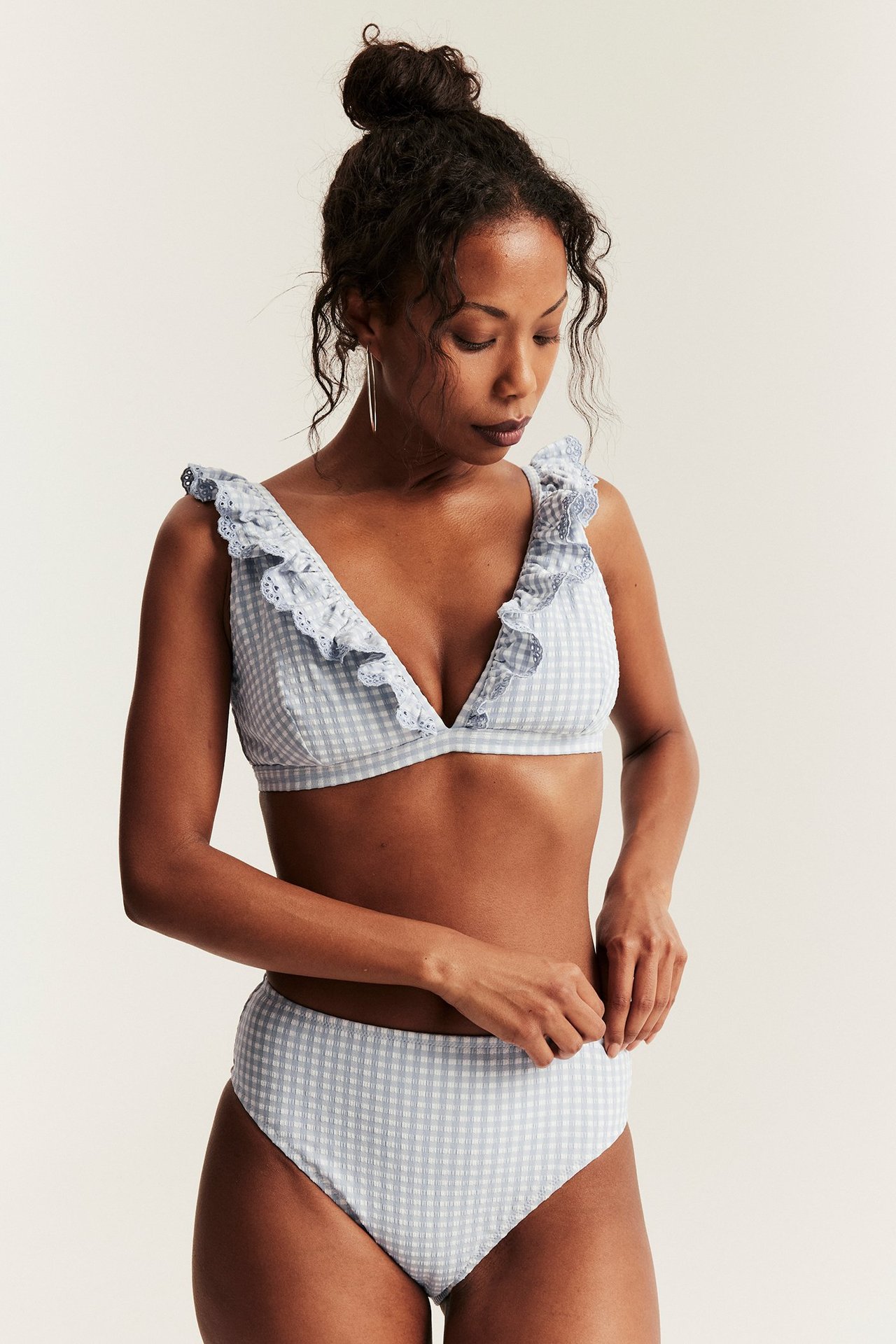 Edestäpäin: Nainen sinivalkoruudullisessa korkeavyötäröisessä bikinialaosassa ja yhteensopivassa röyhelöbikiniliivissä.