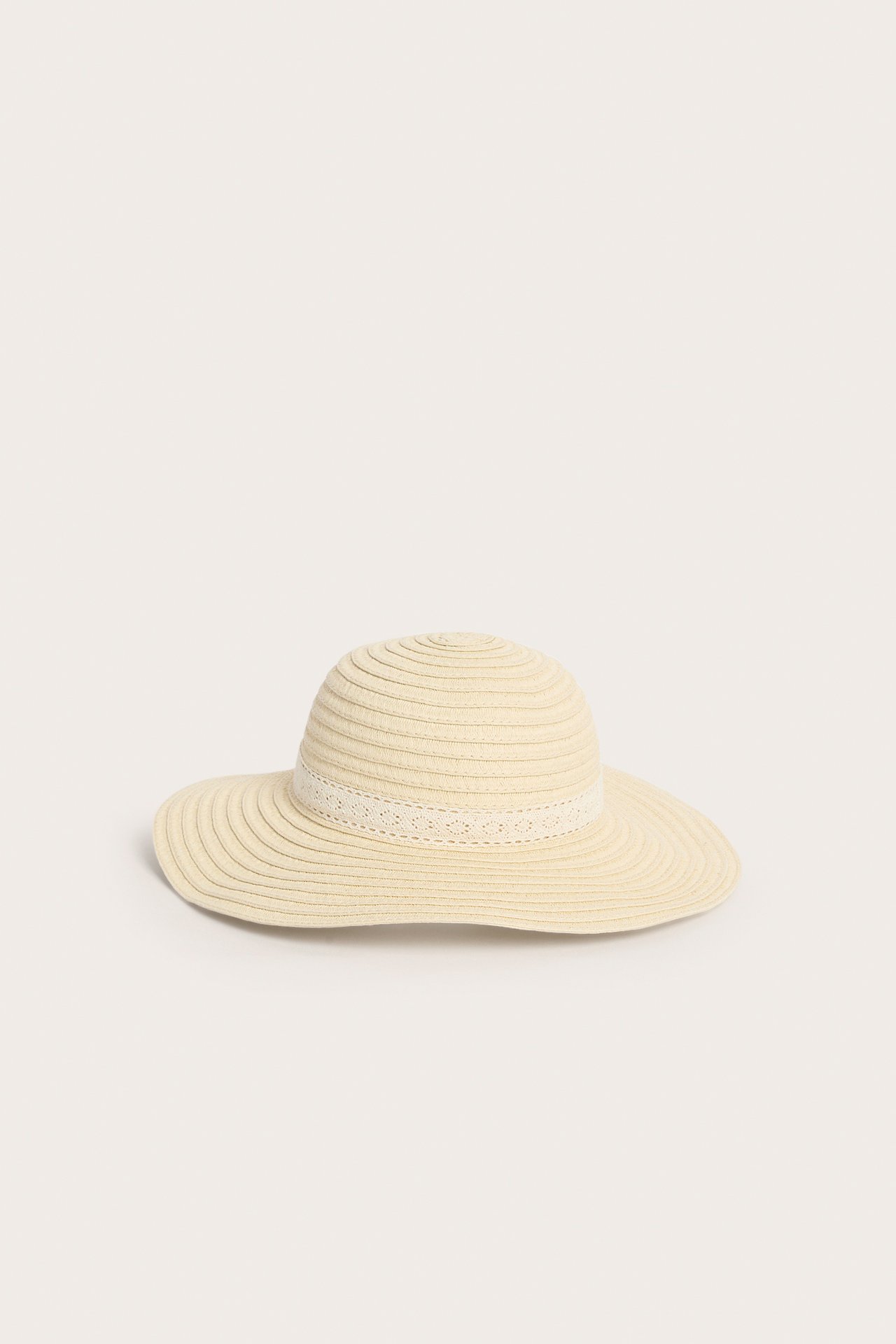 Framifrån, beige stråhatt med ribbad struktur och ett vitt spetsband.