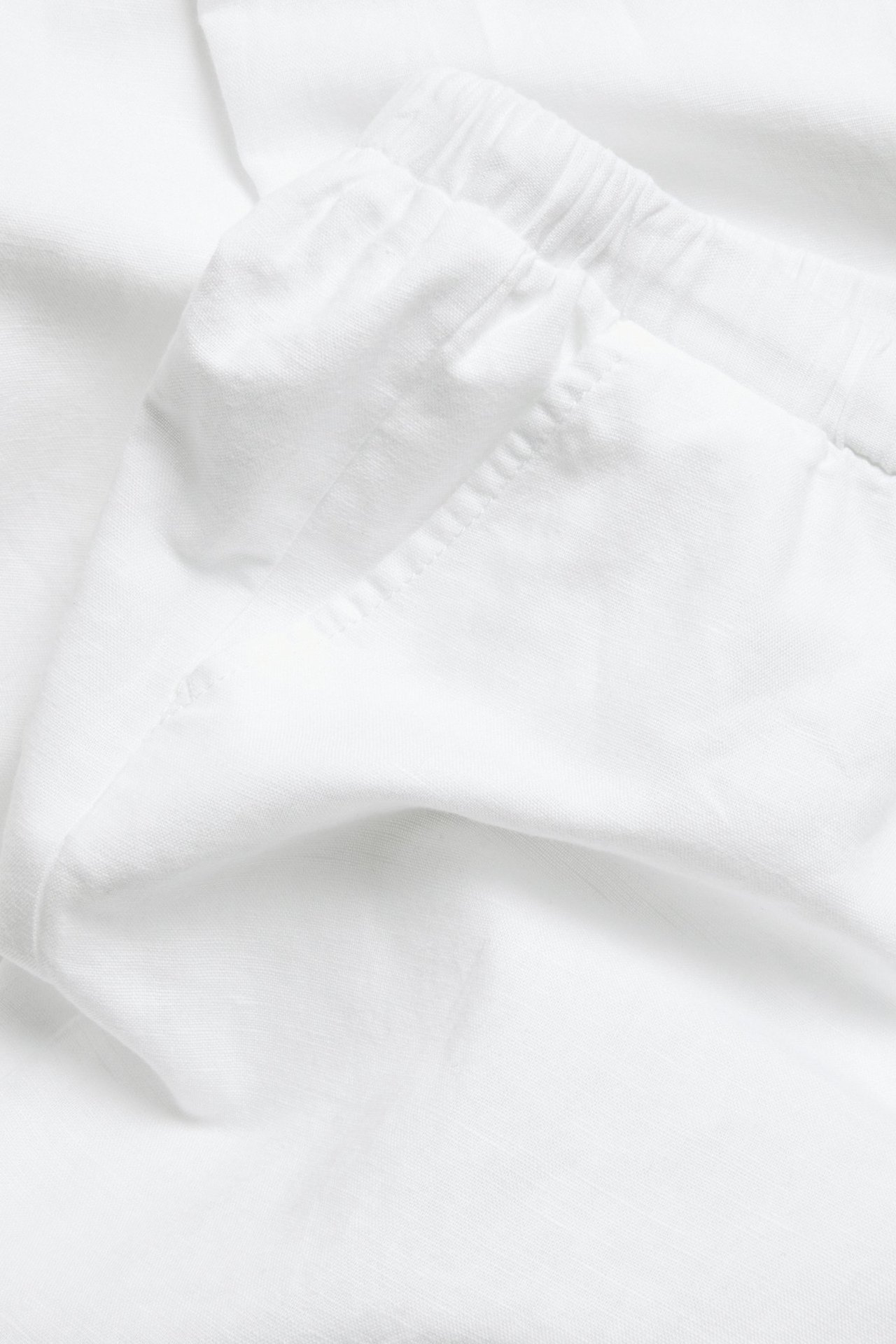 Lähikuva valkoisista pellavasekoitehousuista, joissa näkyy joustava vyötärö ja kankaan rakenne.