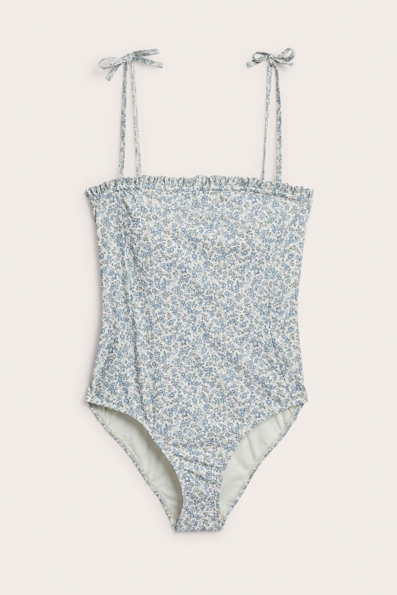 Widok z przodu zielonego kwiecistego kostiumu kąpielowego z falbanką i wiązanymi ramiączkami.