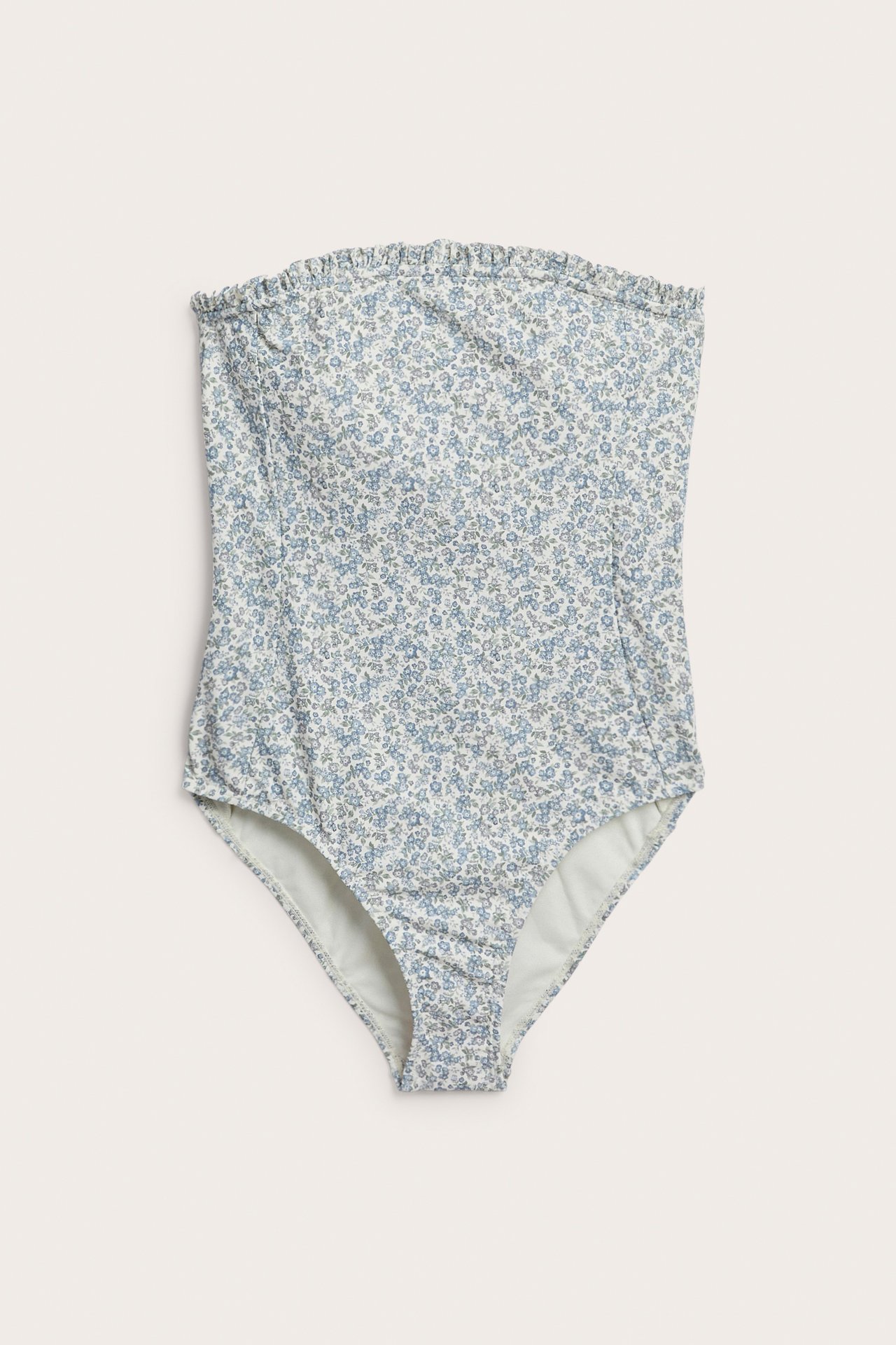 Forfra: Blomstret bandeau-badedrakt for dame i lys blått med volangkant øverst.