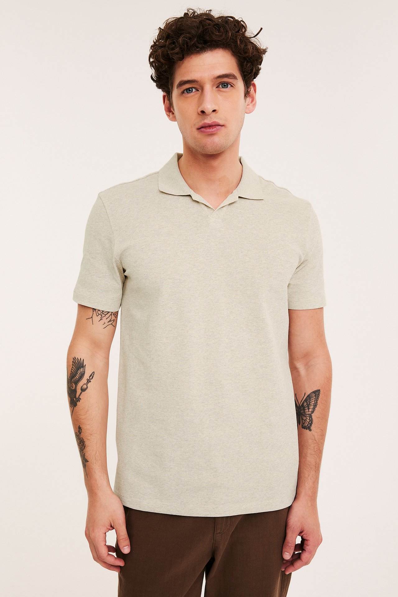 Frontbilde: mann i beige melert pikéskjorte med V-hals, stylet med brune bukser.