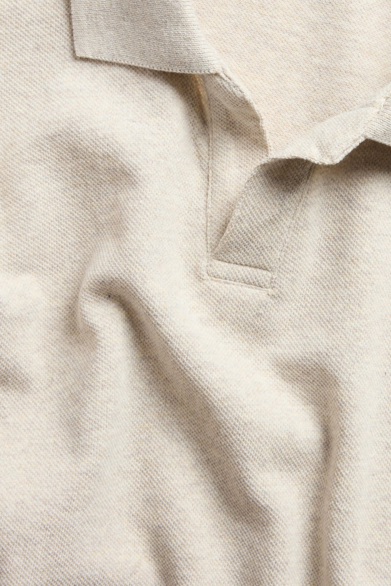 Zbliżenie beżowej melanżowej koszulki polo z piki z kołnierzykiem i dekoltem w serek.