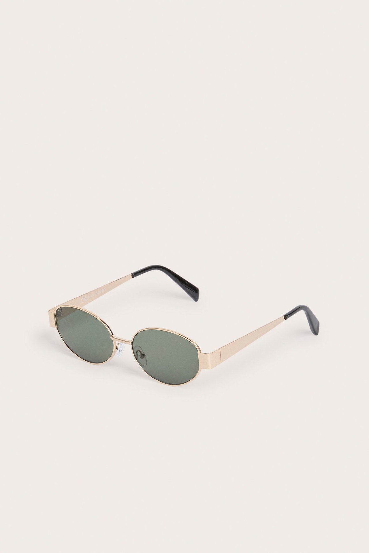 Frontvy av ovala solglasögon i guld med mörka linser och svarta skalmar.