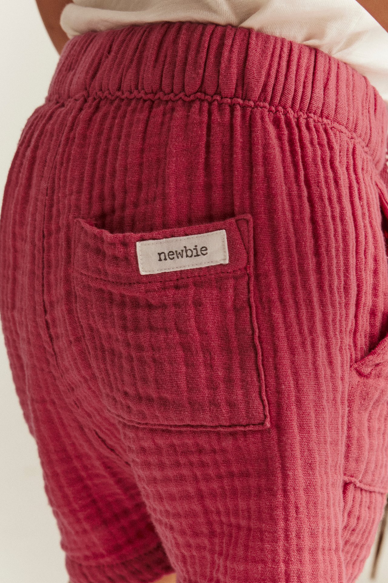 Närbild bakifrån på barn i röda vävda bomullsshorts med resår i midjan och påsydd bakficka.