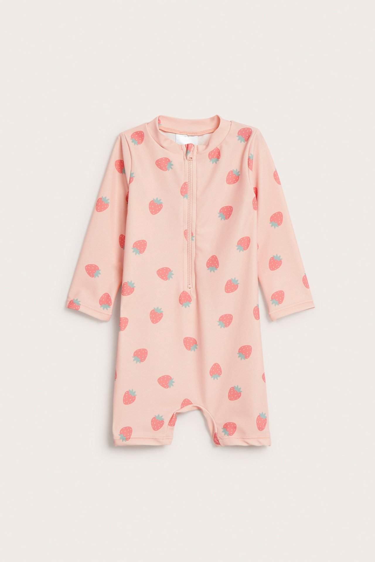 Edestä: vauvan vaaleanpunainen UV-asu, pitkät hihat, lyhyet lahkeet, mansikkaprintti ja vetoketju edessä.