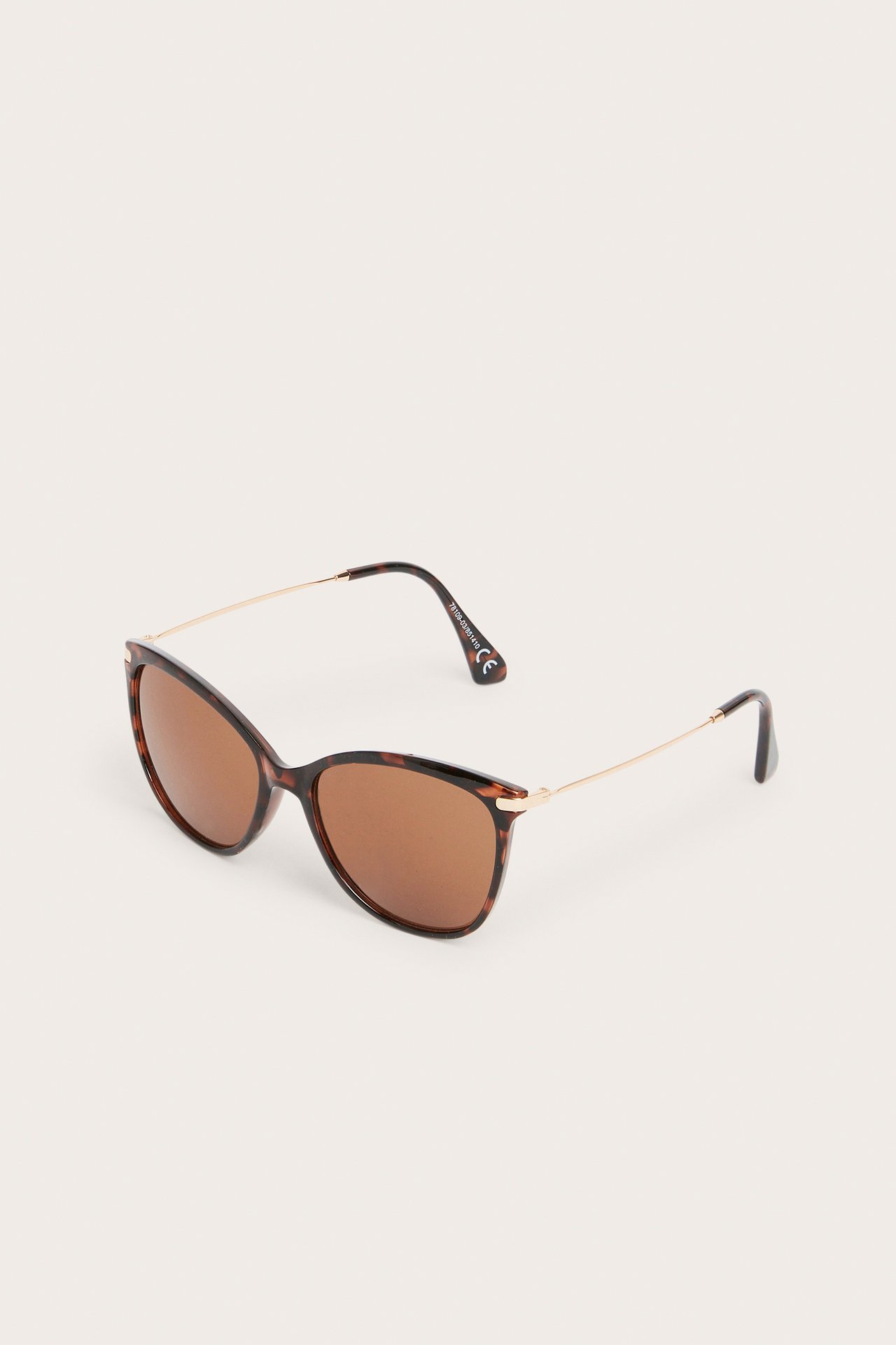 Sned frontvy av bruna sköldpaddsmönstrade kattögon-solglasögon med tunna guldfärgade metallskalmar.