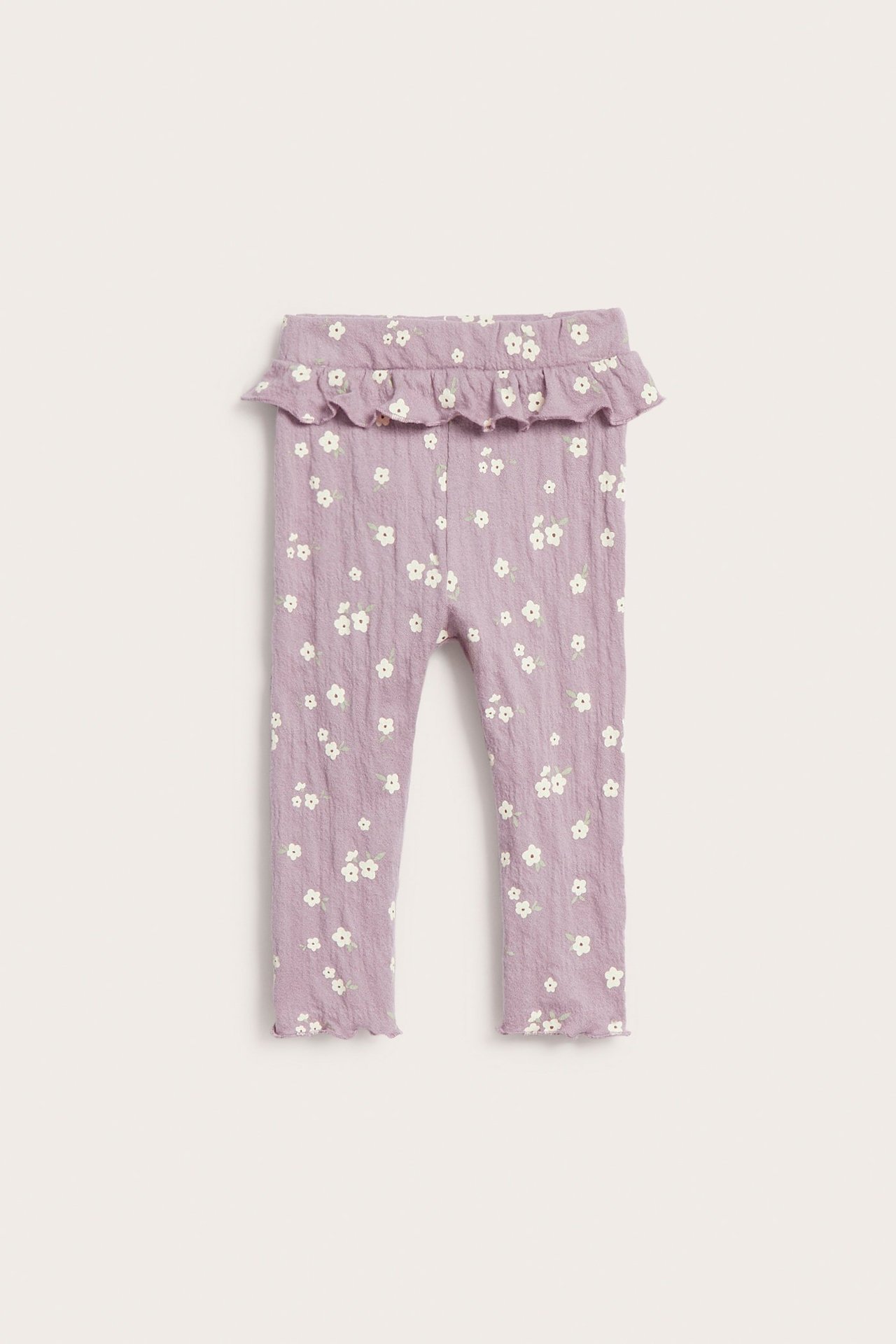 Frontvy av babyens lilla crepe leggings med blomstermønster, volang i midjen og bølgete benåpninger.