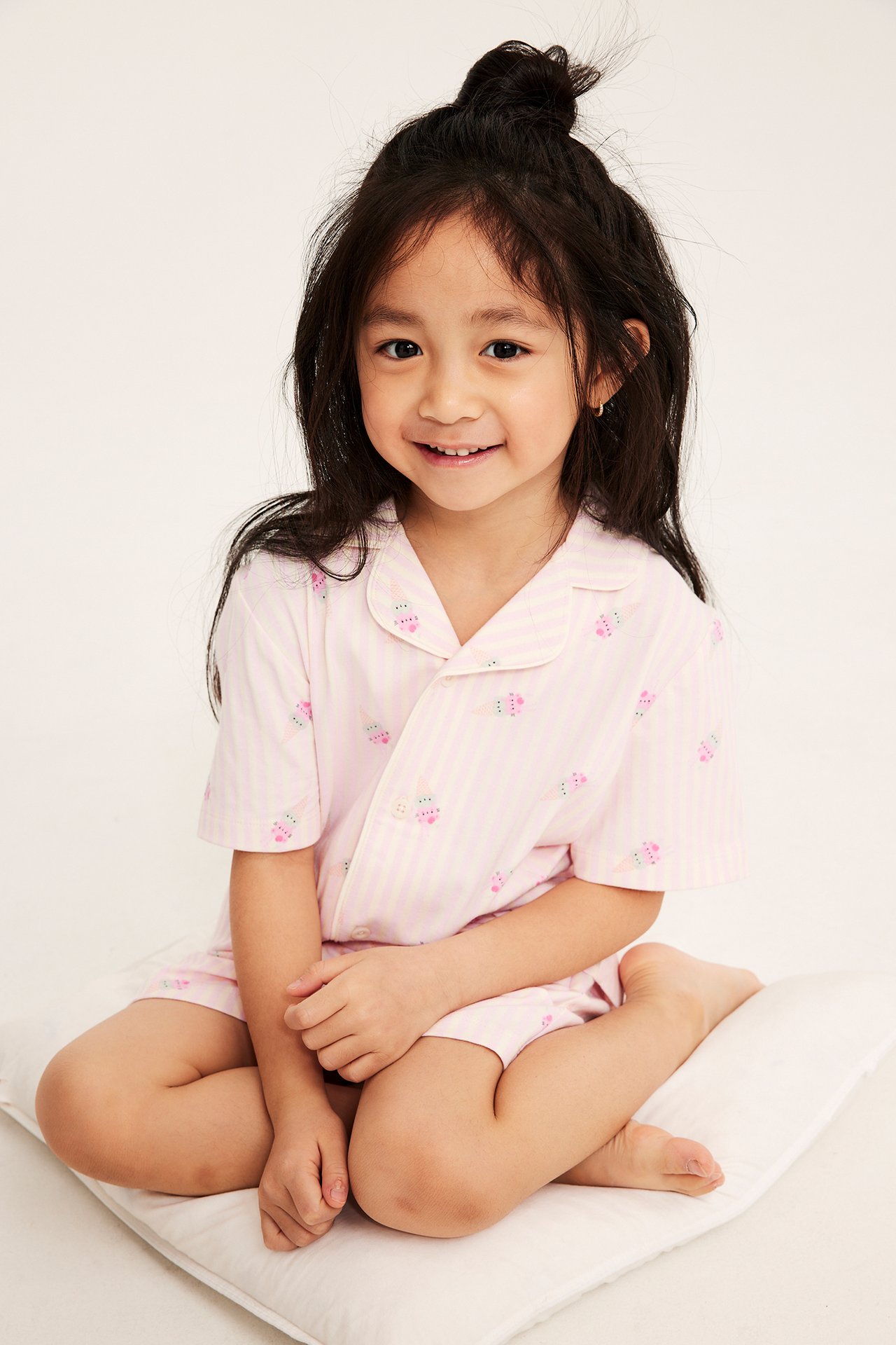 Forfra, et barn i stripete offwhite og rosa bomullspysj med ismønster.