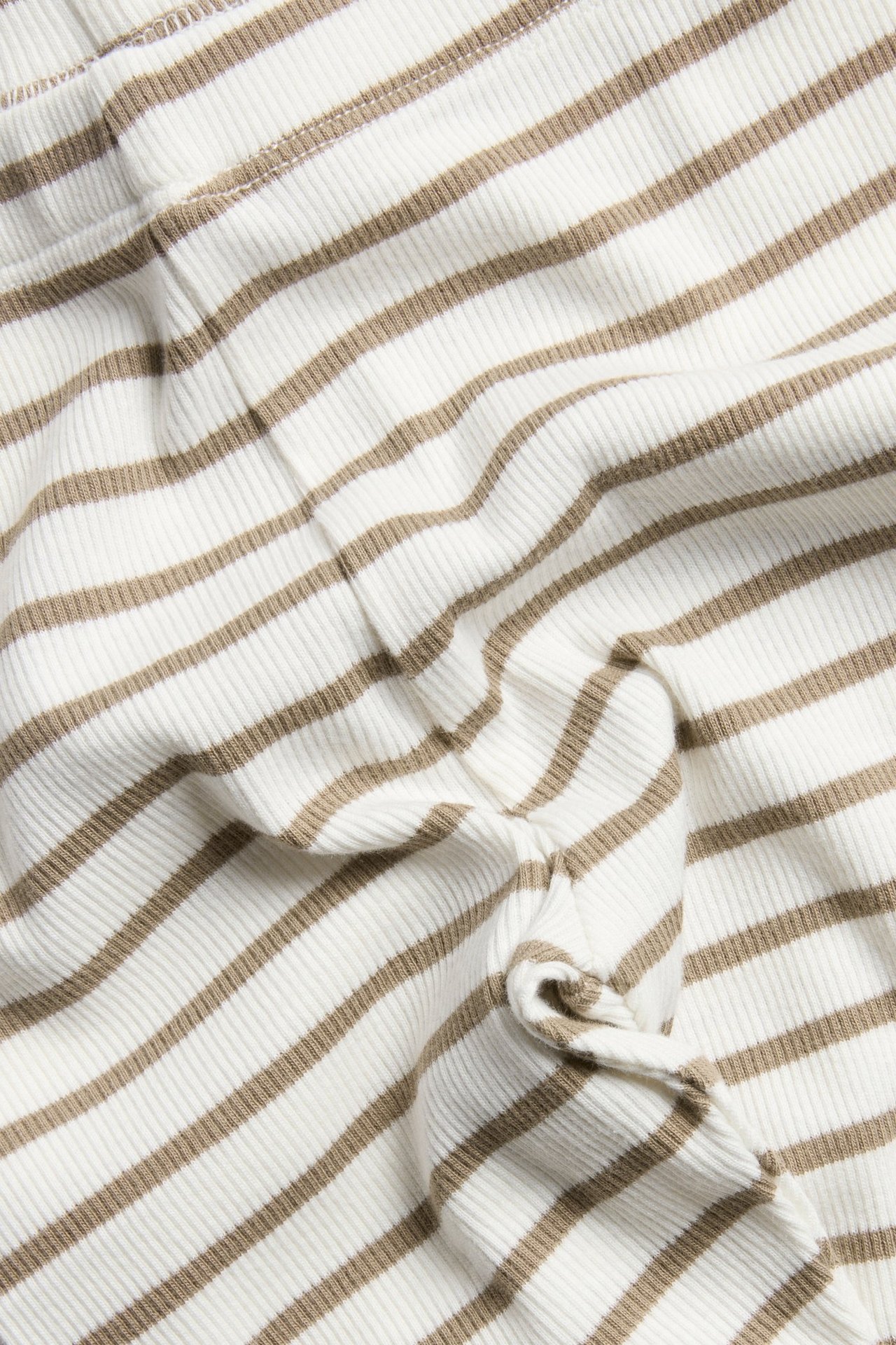 Zbliżenie na prążkowane legginsy w paski ecru i brązowe z elastycznym pasem.