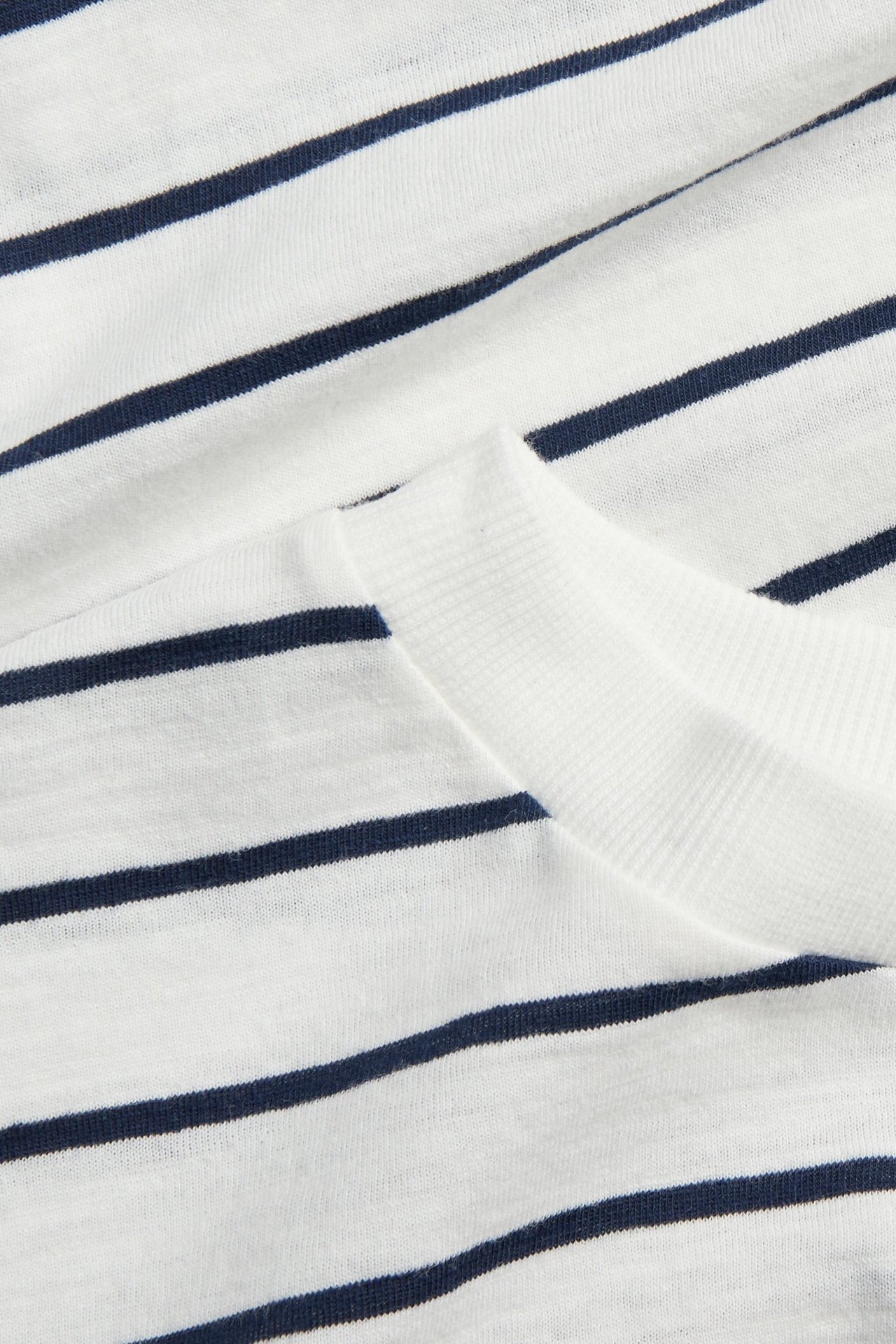 Zbliżenie na białą bawełnianą koszulkę w granatowe paski z prążkowanym dekoltem.
