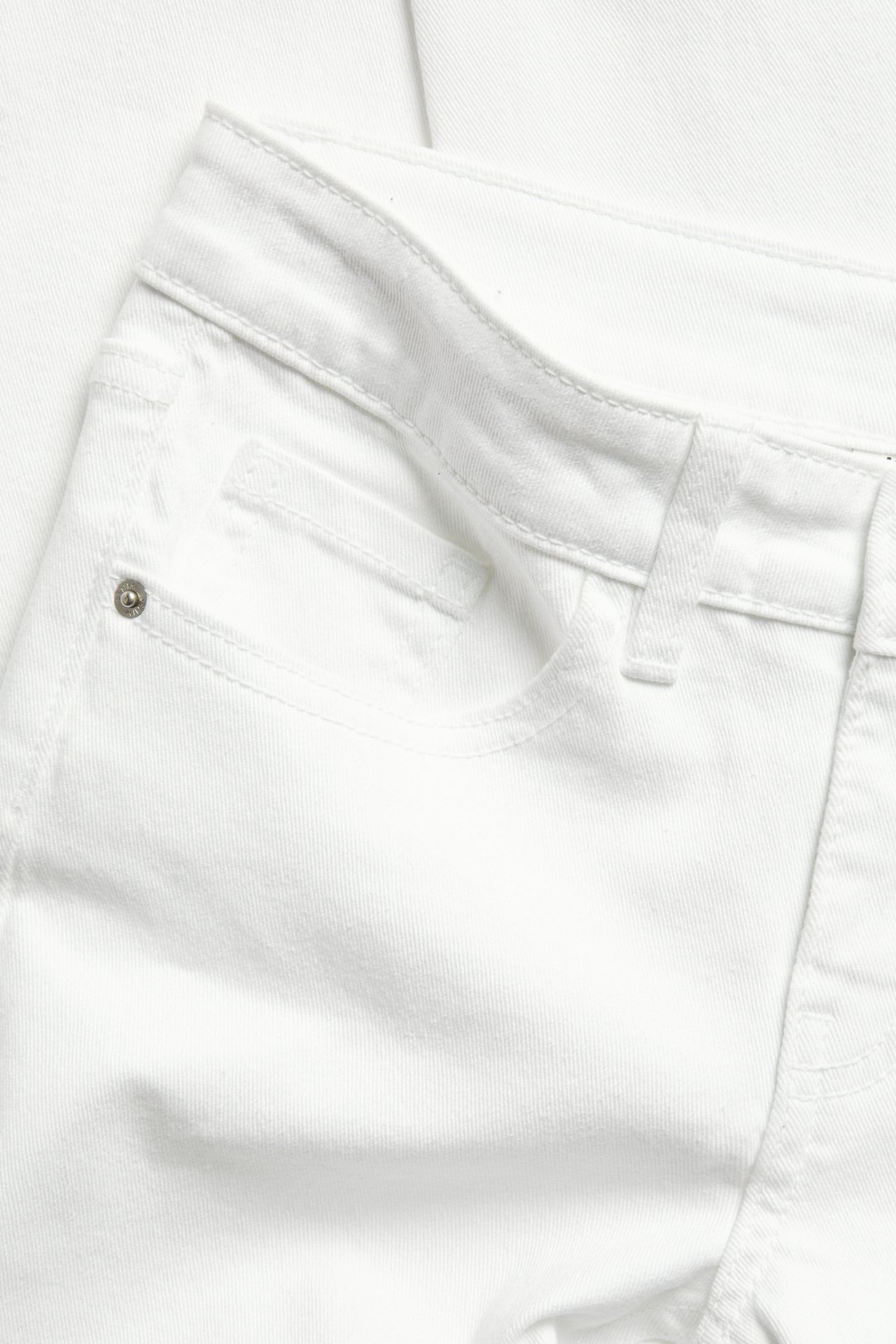 Nærbilde forfra av hvite bomullsblandede bootcut-jeans med lavt liv, frontlomme og sølvnagle.
