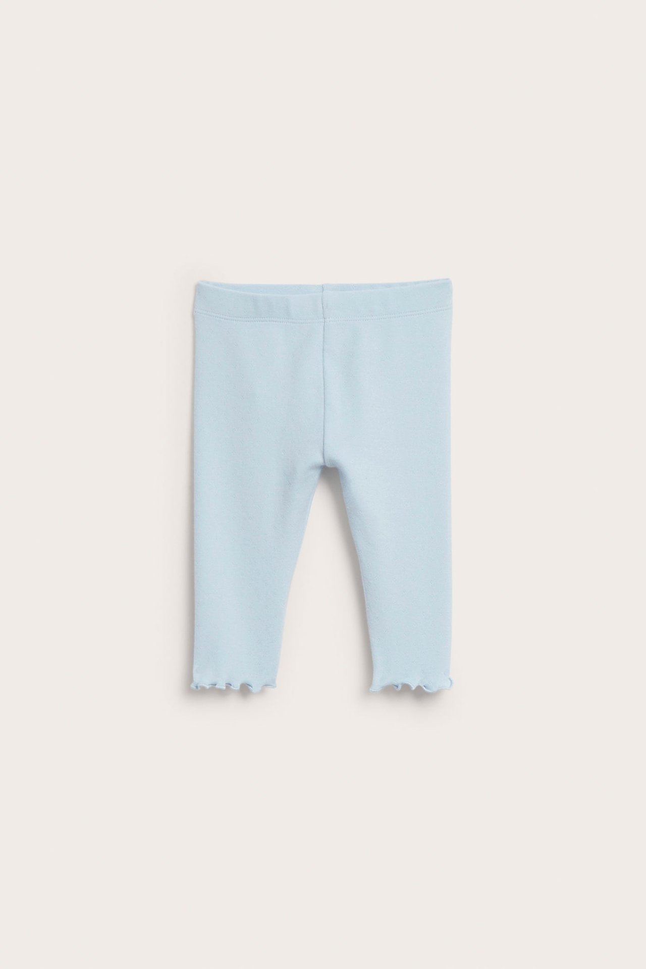 Framifrån, ljusblå pointelle stickade baby leggings med en picotkant vid benslutet.