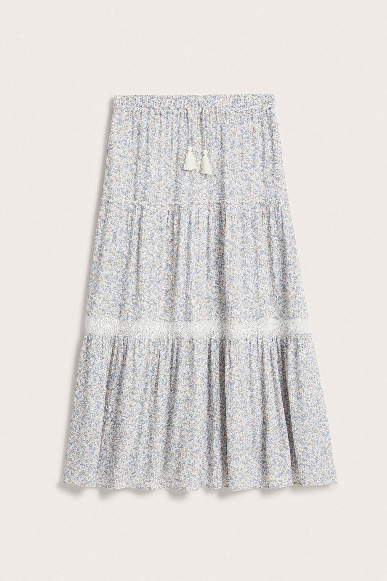 Widok z przodu: Długa spódnica off-white w kwiaty z koronką, elastyczną talią i frędzlami.