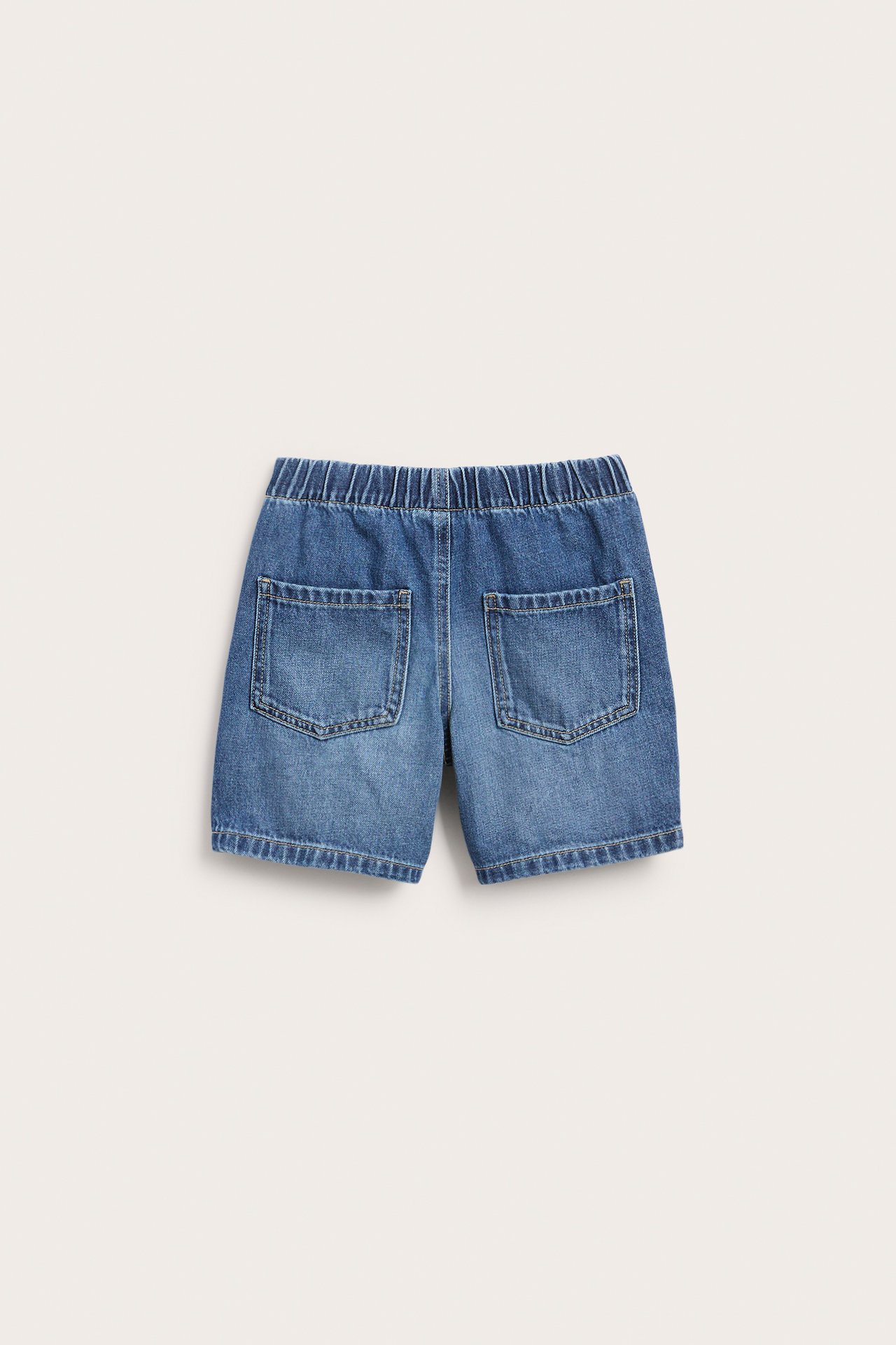 Mjuka mörkblå jeansshorts för barn, bakifrån, med resår i midjan och två bakfickor.