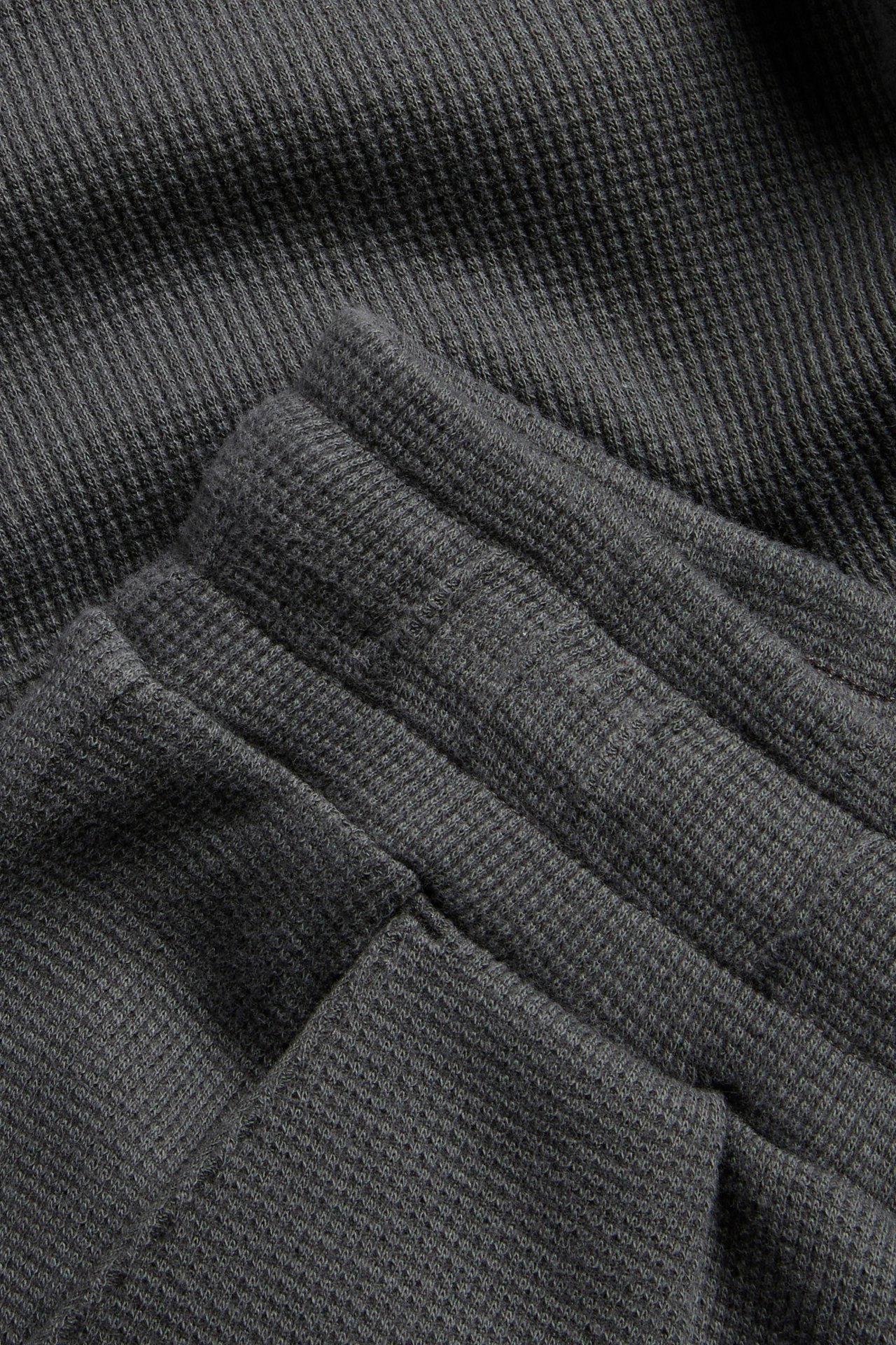 Nærbilde av svarte vaffelmønstrede bomullsshorts med en fremtredende elastisk linning.