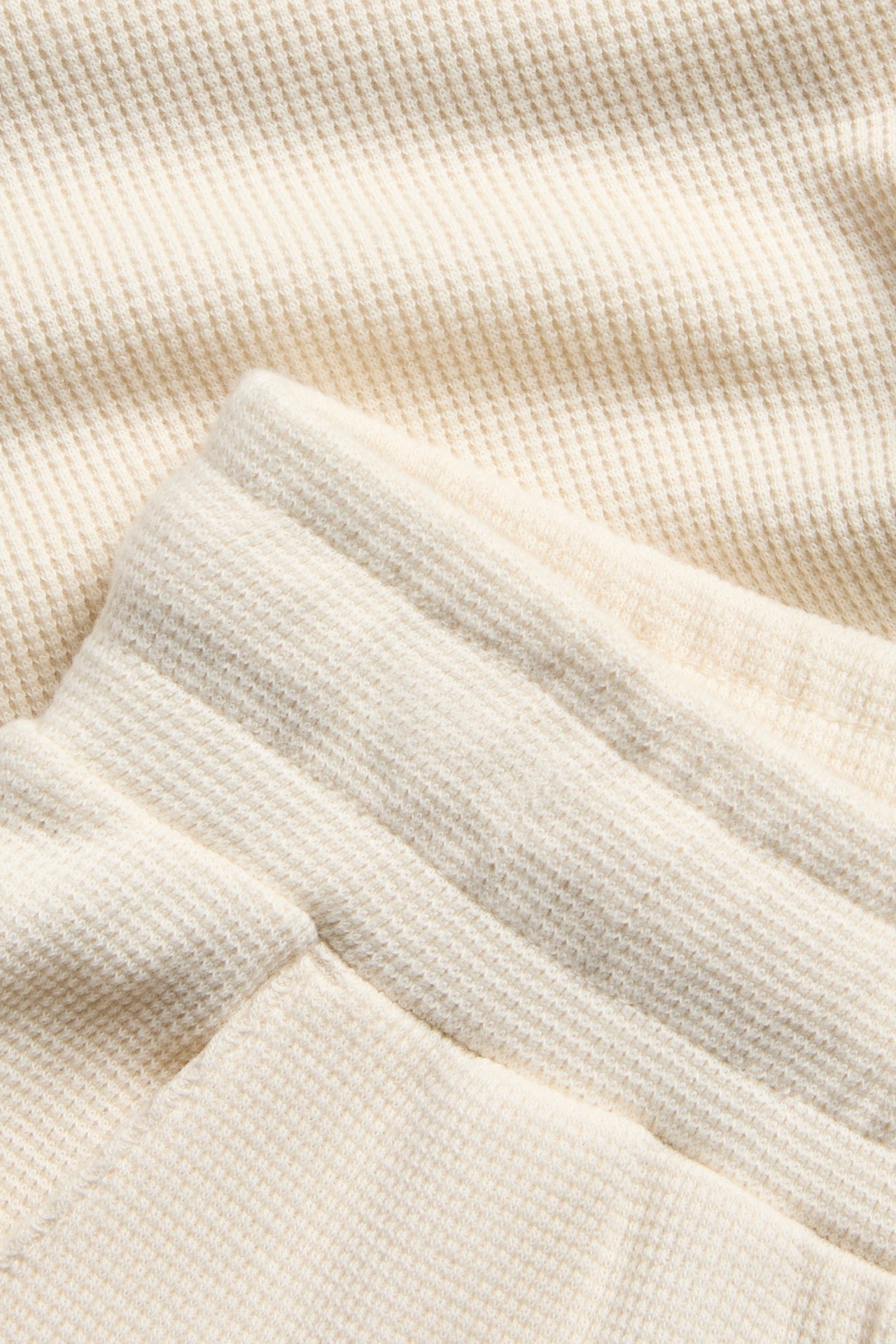 Nærbilde av lysbeige vaffelstrikkede bomullsshorts som viser den elastiske linningen.