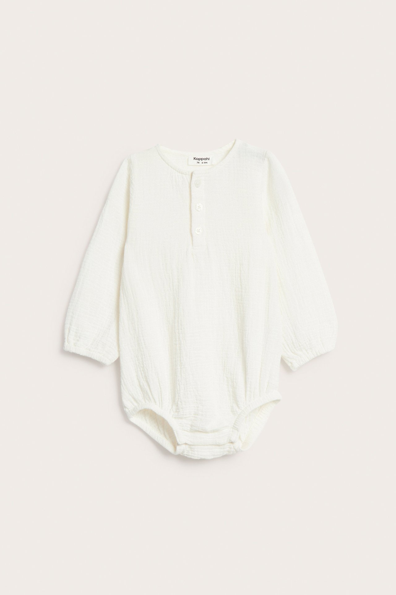 Edestäpäin, luonnonvalkoinen pitkähihainen vauvan musliinihaalari paitanapeilla ja neppareilla.