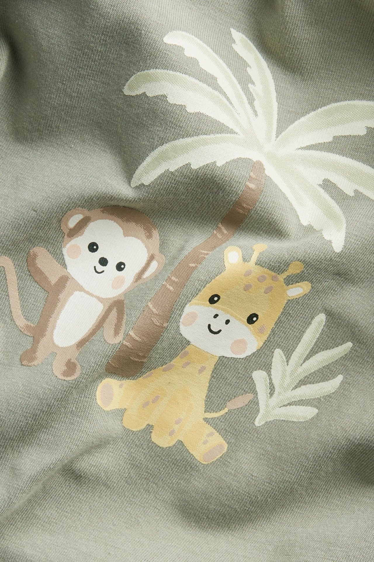 Nærbilde av mørkegrønn kortermet babybody med trykk av beige ape, gul sjiraff og palme.