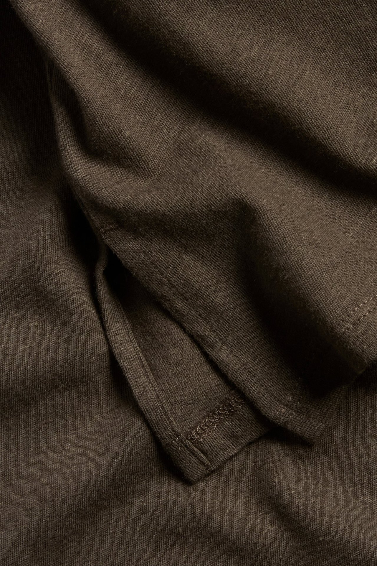 Zbliżenie brązowego topu z mieszanki lnu i bawełny, ukazujące jego fakturę i subtelne rozcięcie z boku.