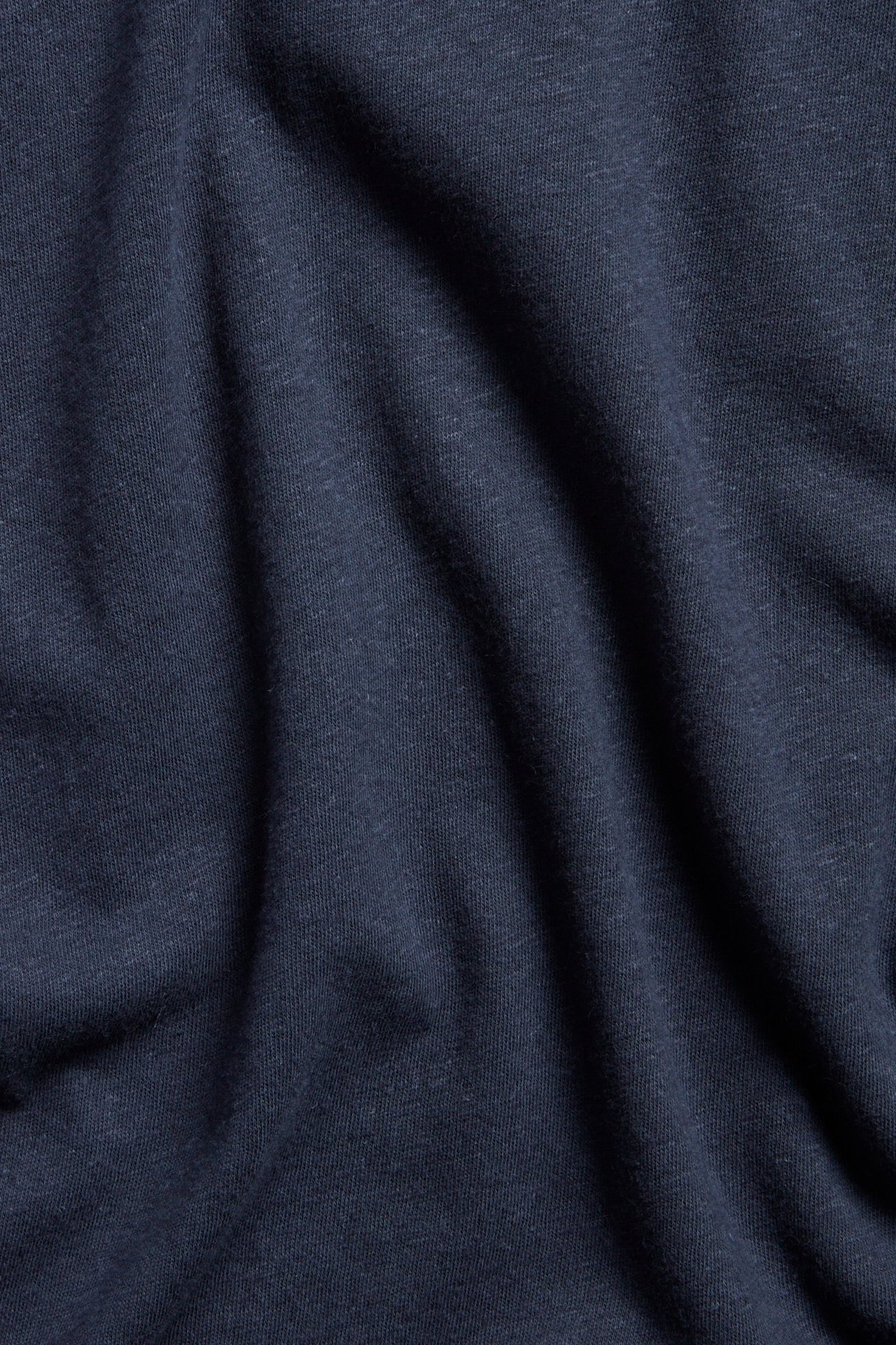 Närbild av mörkblå enfärgad tanktopp i linne- och bomullsblandning med veck.