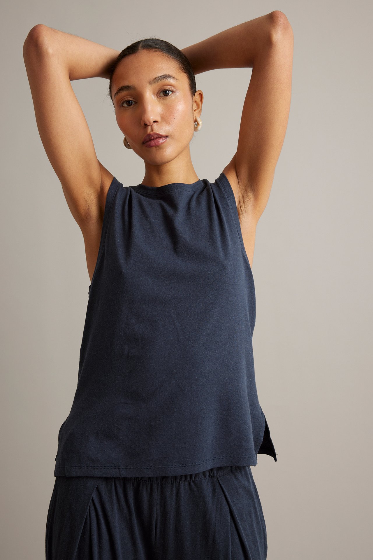 Frontvy av kvinna i mörkblå linneblandad tanktop med sidoslitsar, stylad med matchande culottebyxor.