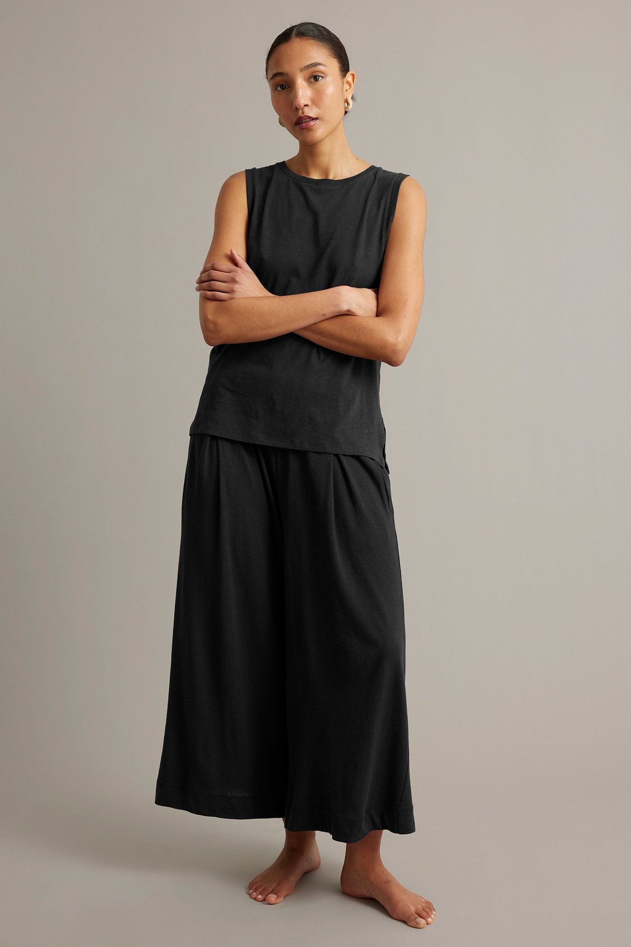 Frontvy av en kvinna i ett svart linne av bomull/linne och matchande vida culottebyxor.