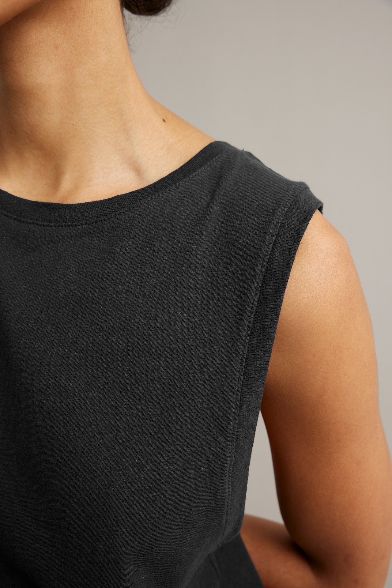 Närbild av en kvinna i svart linneblandad tanktop med rund halsringning.