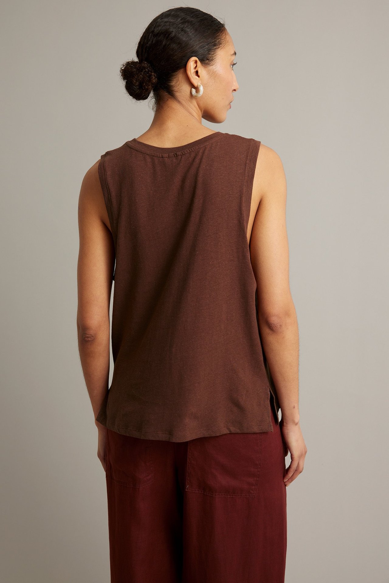 Ryggvy av en kvinna i ett vinrött linne i linne-/bomullsblandning och mörkröda culottebyxor.