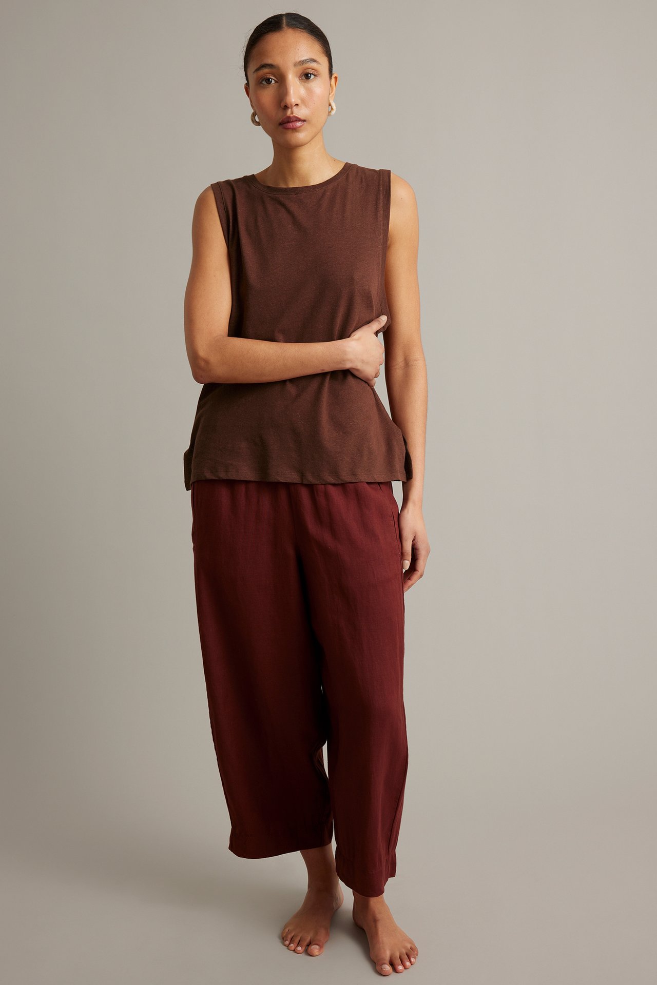Framifrån: kvinna i mörkt vinröd linneblandad tanktopp och matchande vinröda culottebyxor.