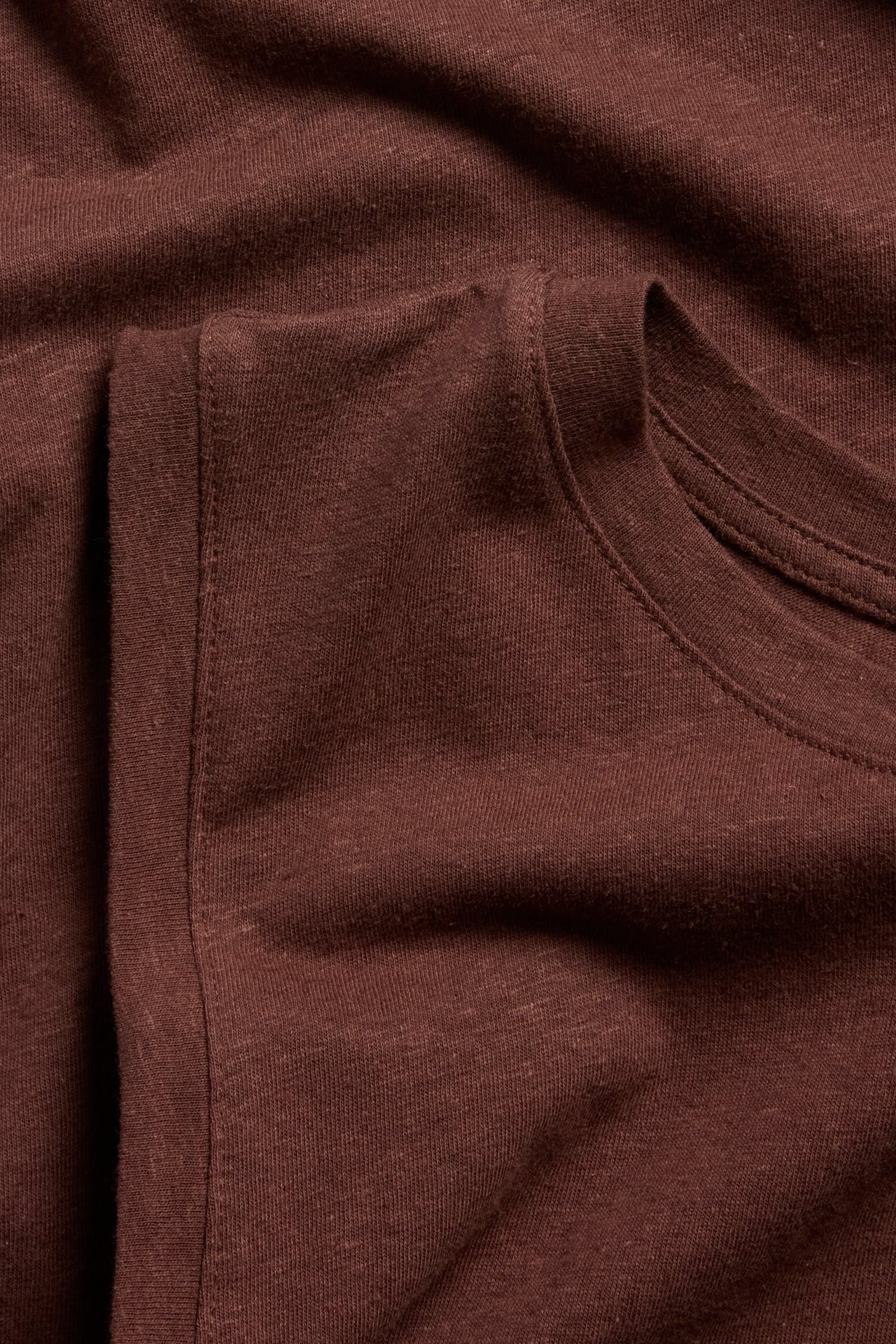 Närbild av ett vinrött linne i linne- och bomullsblandning, visar halsringning och axelsöm.