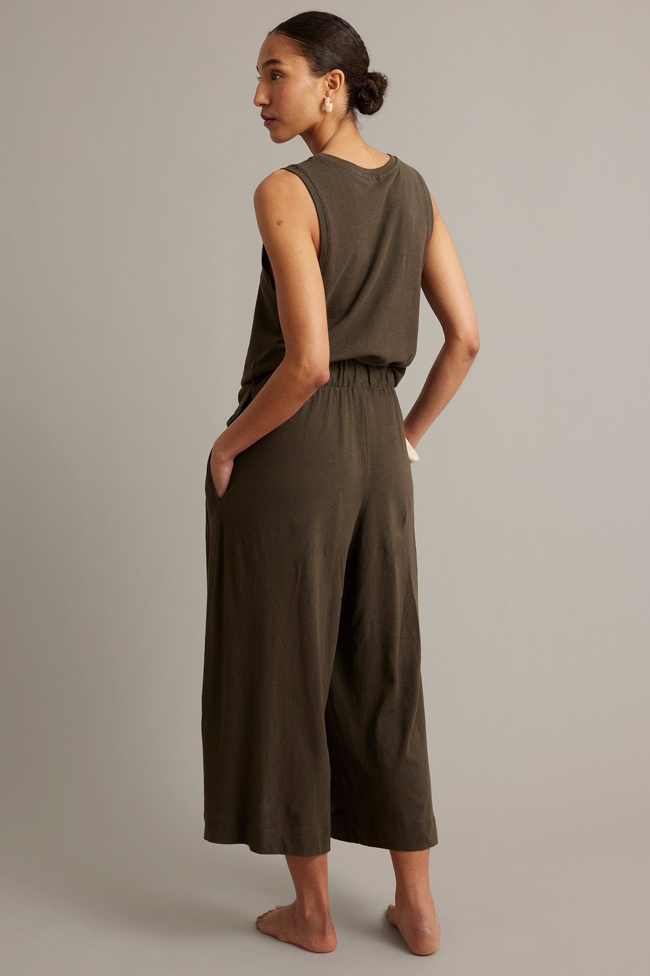 Kvinna bakifrån i bruna linneblandade culottebyxor med resår, sidfickor och matchande ärmlös topp.