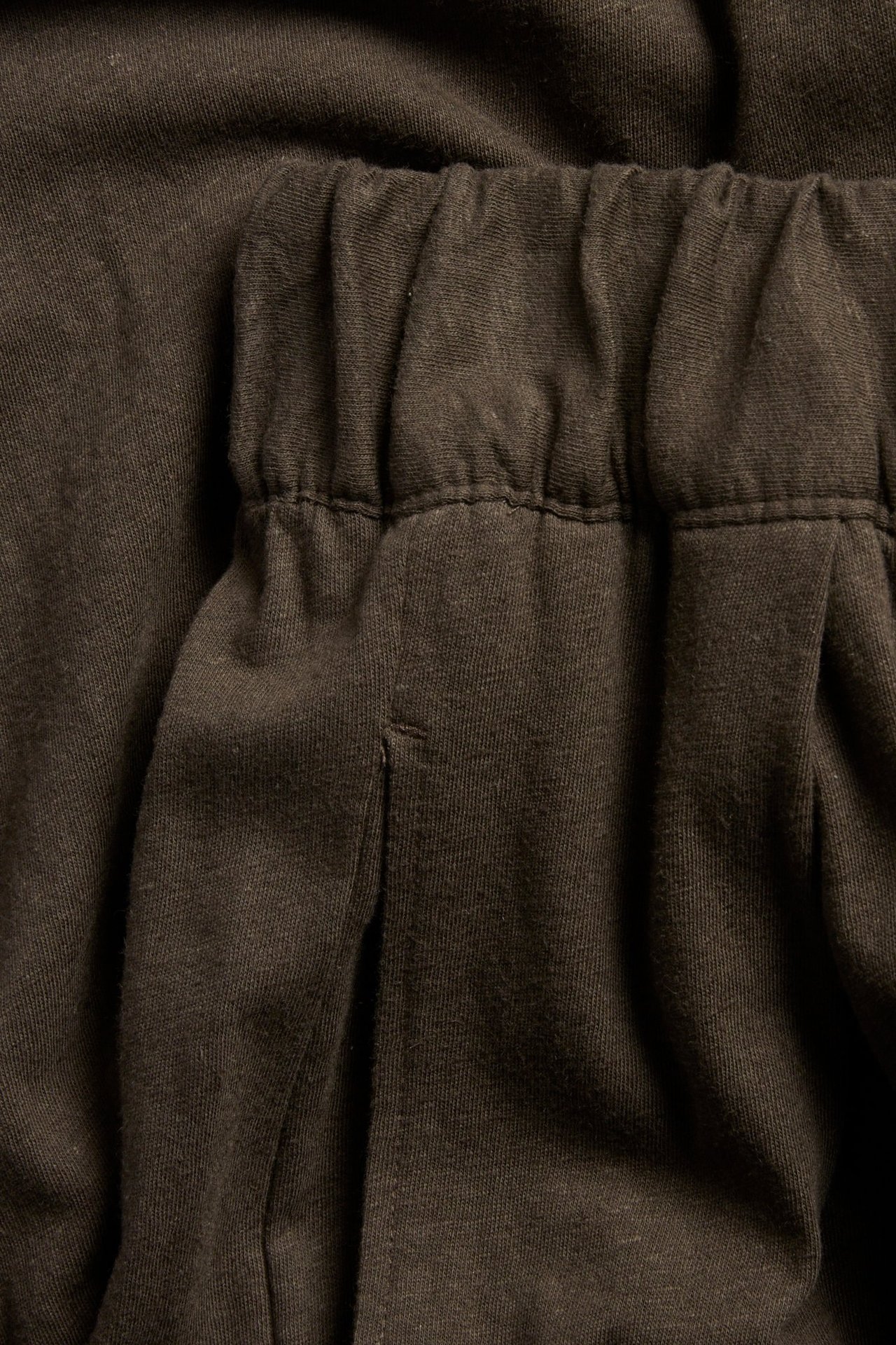 Zbliżenie brązowych dżersejowych spodni culotte z bawełny i lnu z elastycznym pasem i zakładkami.