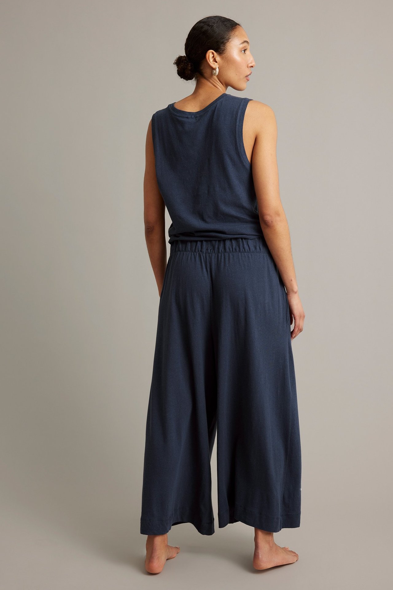 Bakifrån: Kvinna i mörkblå culottebyxor i bomull-linne med resår i midjan och matchande ärmlös topp.