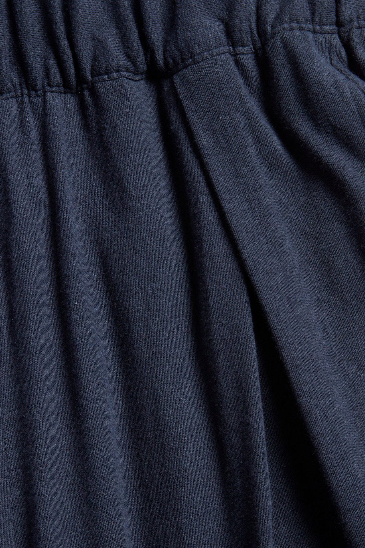 Närbild på mörkblå culottebyxor i bomull-linne med resår i midjan och veck fram.