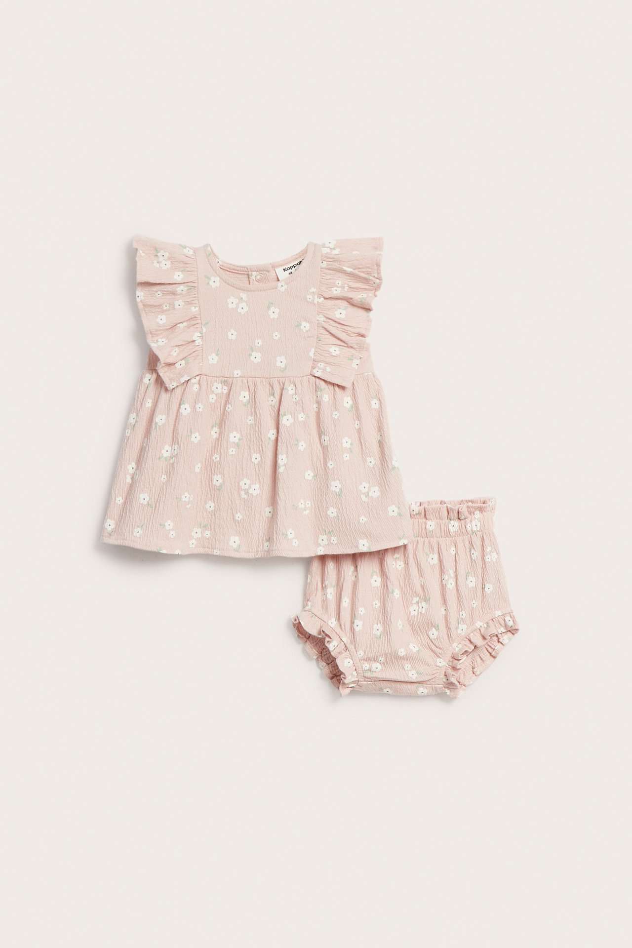Edestäpäin: vauvan vaaleanpunainen puuvillatoppi kukkakuviolla ja röyhelöiset bloomersit.